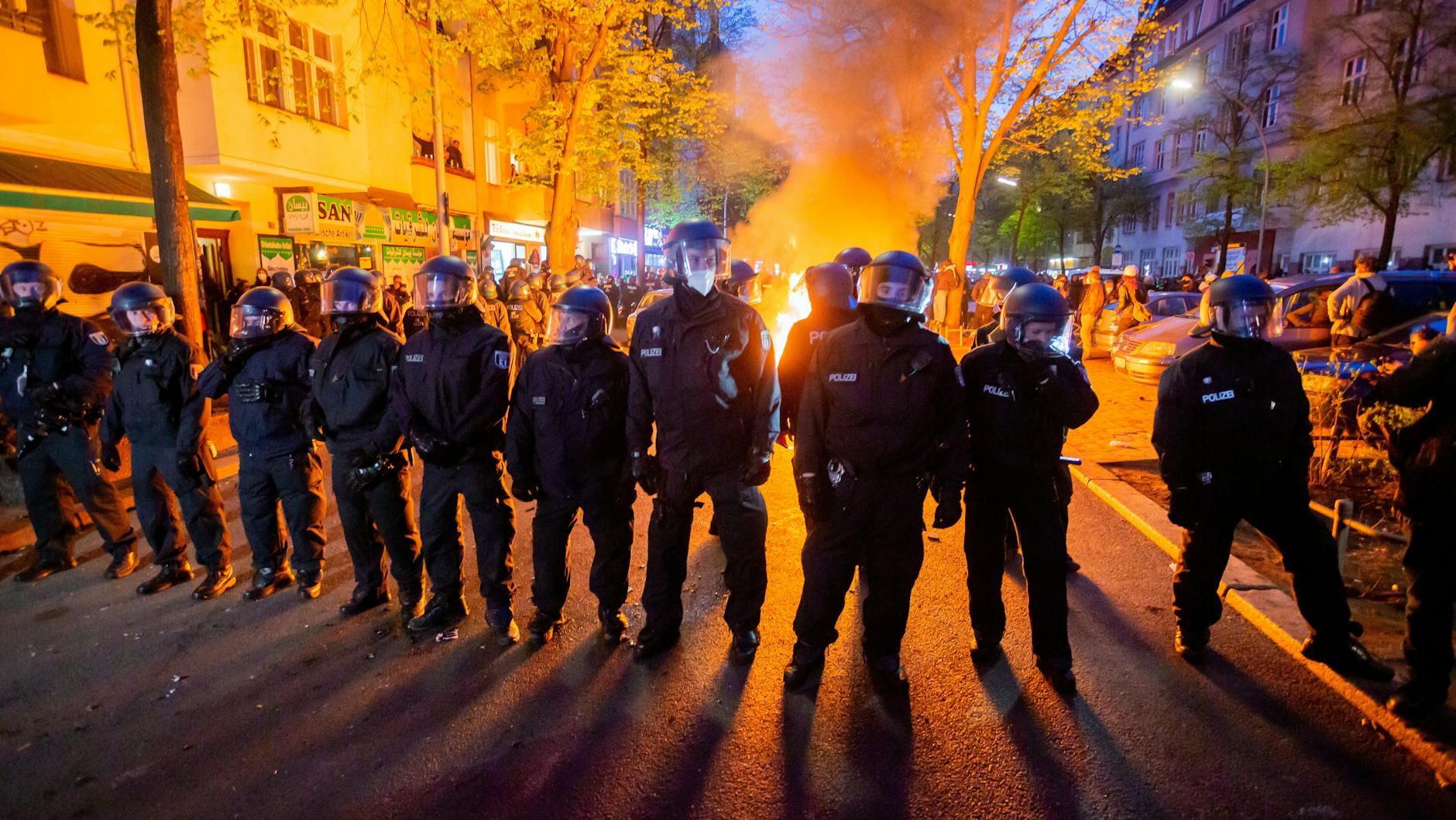 Polizisten stehen am 1. Mai 2021 vor einem Feuer auf der Straße am Rande der Demonstration linker und linksradikaler Gruppen.
