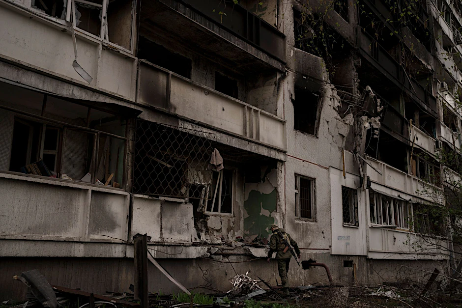 Ein ukrainischer Soldat steht nach einem russischen Angriff vor einem beschädigten Wohnhaus.
