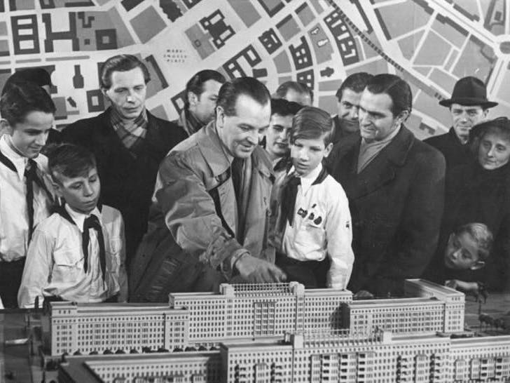 Szene aus dem Defa-Kulturfilm „Die neue Wohnung“: Der Architekt und Nationalpreisträger Richard Paulick (Mitte) erklärt 1953 den Aufbau der Wohnblöcke.