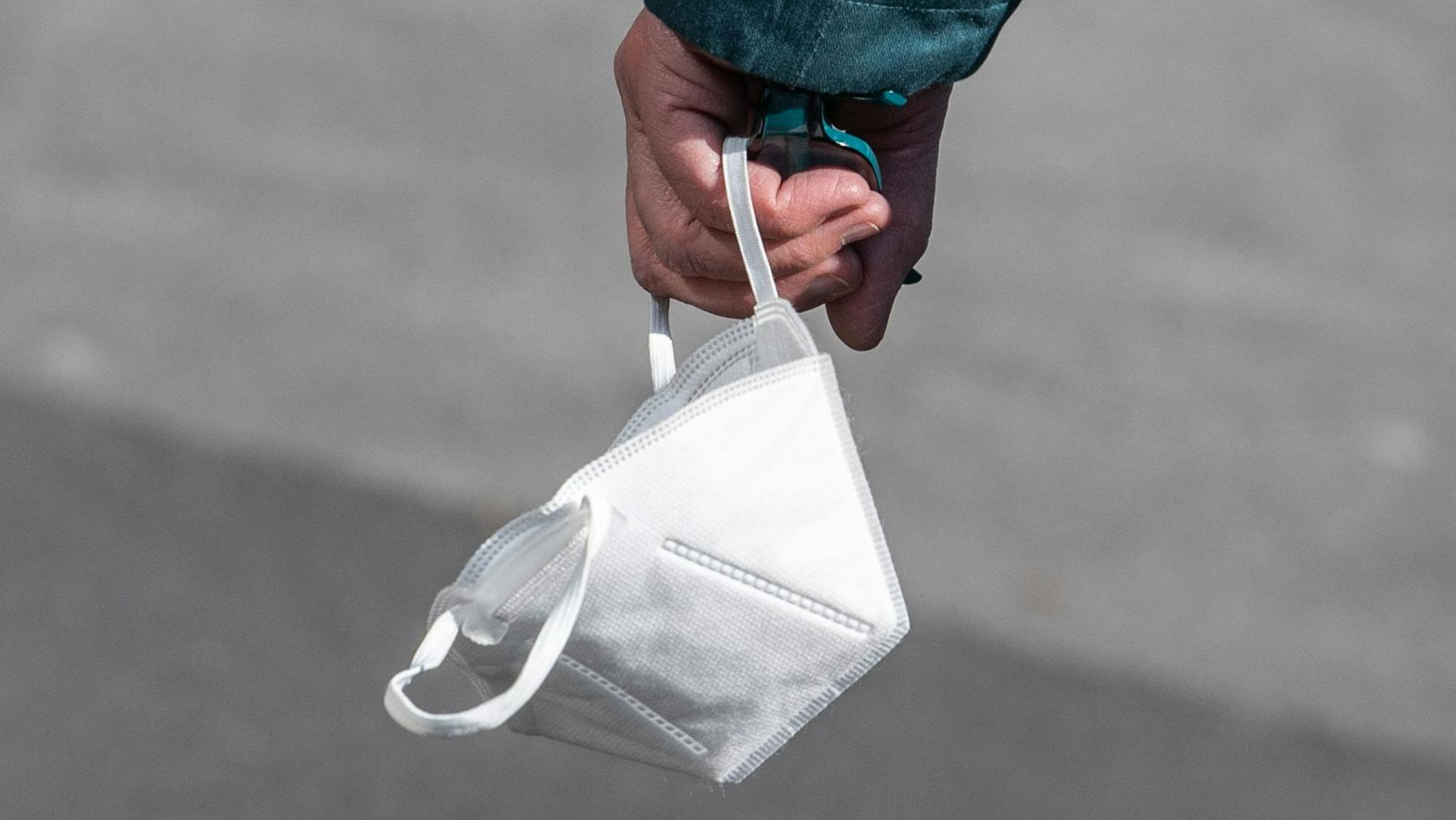 Ein Passant trägt eine FFP2-Maske in der Hand.