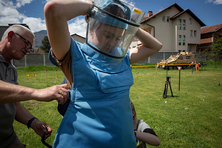 Anastasia Mintschukowa (r.) legt sich einen Schutzanzug und ein Visier an. Sie gehört zu einer Gruppe ukrainischer weiblicher Einsatzkräfte, die eine Spezialausbildung in der Kampfmittelbeseitigung und eine Vermessungsausbildung absolvieren.