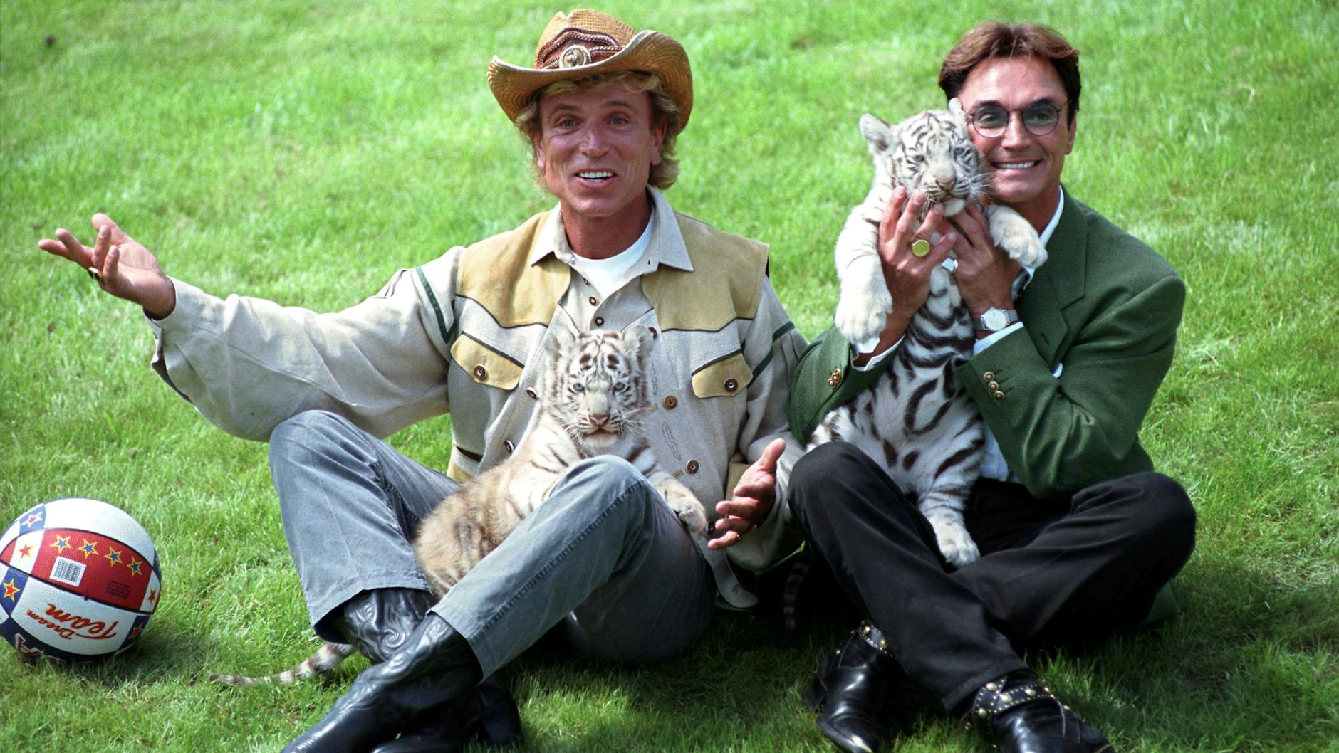 Die deutschen Magier Siegfried (l.) und Roy stellen sich im Hollywood-Safari-Park mit zwei weißen Tiger-Jungen den Fotografen vor. Hunderte Erinnerungsstücke aus dem Besitz des verstorbenen Zauber-Duos Siegfried und Roy sollen im Juni 2022 in Kalifornien versteigert werden.