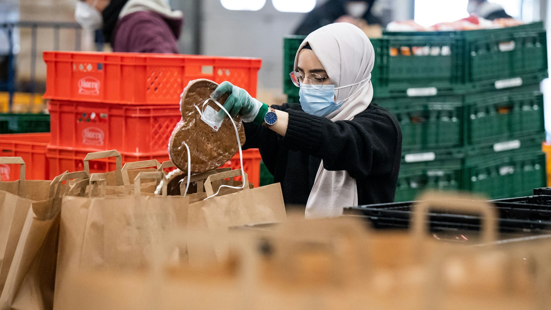 Eine Helferin legt in einer Halle der Berliner Tafel auf dem Berliner Großmarkt Lebensmittel in Papiertüten.