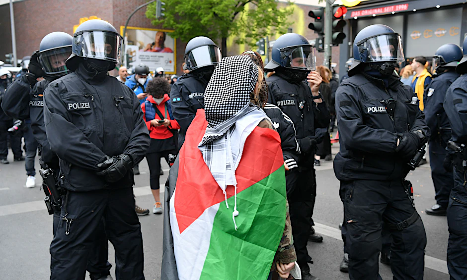 Die „Revolutionäre 1. Mai-Demo“: eine Teilnehmerin mit Palästinenser-Tuch und Flagge