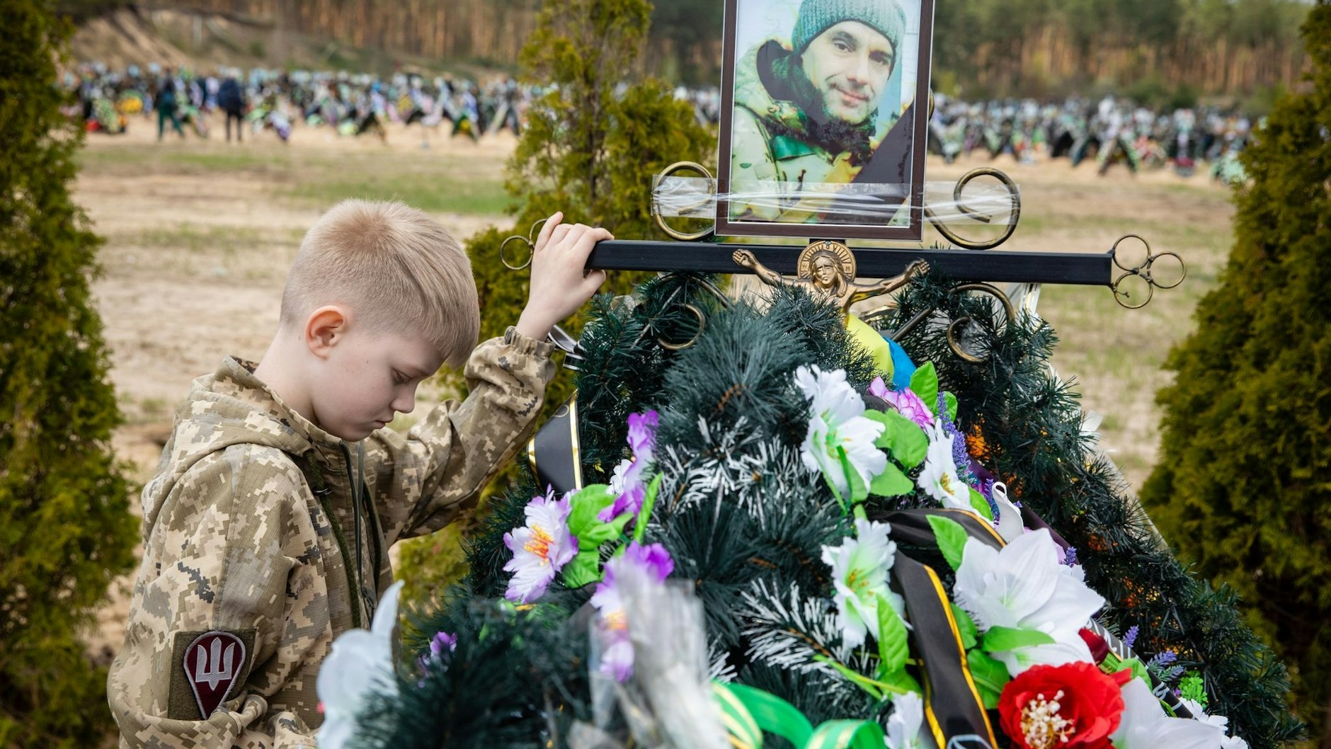 Savelii (10) steht am Grab seines Vaters Igor, der bei der Verteidigung der Stadt Irpin als Mitglied der Territorialverteidigung getötet wurde. 