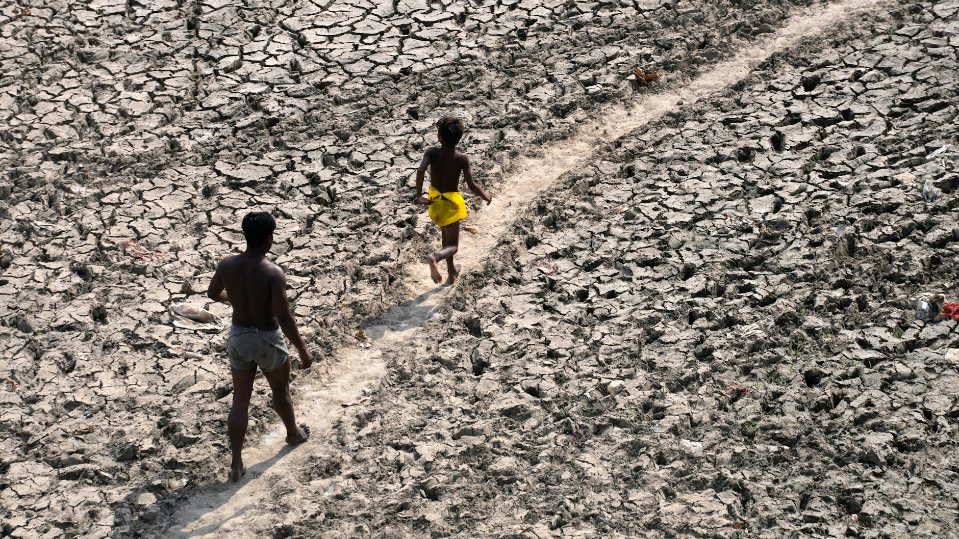 Ein Mann und ein Junge laufen durch das jetzt trockene Flussbett des Yamuna River, ein Nebenfluss des Ganges.