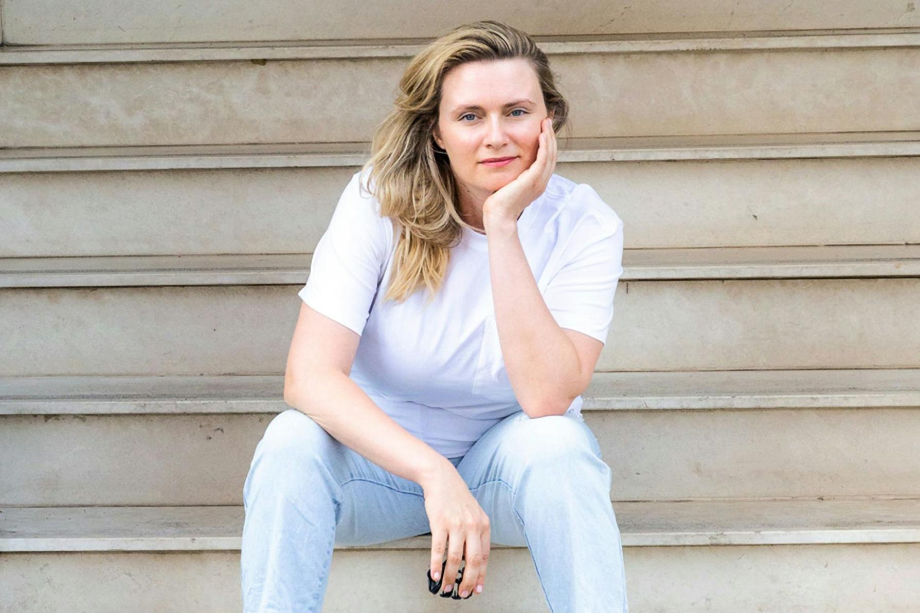 Die im Kreis Minden nahe der Grenze zu Niedersachsen lebenden Schriftstellerin Elina Penner sitzt auf einer Treppe.