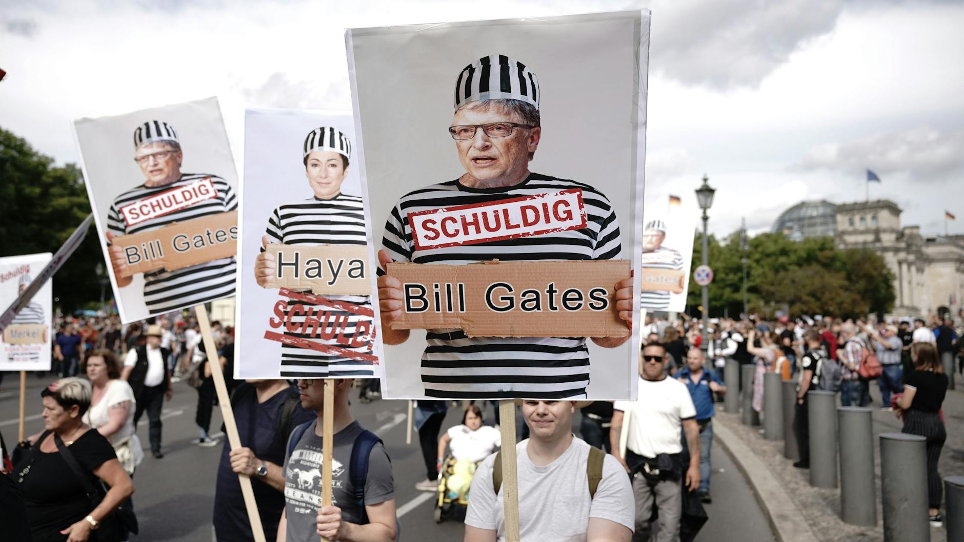 Teilnehmer einer Demonstration gegen die Corona-Maßnahmen in Berlin halten Schilder mit Fotos von Politikern, Journalisten und Wissenschaftlern jeweils mit Namen und „Schuldig“, rechts Microsoft Gründer Bill Gates.