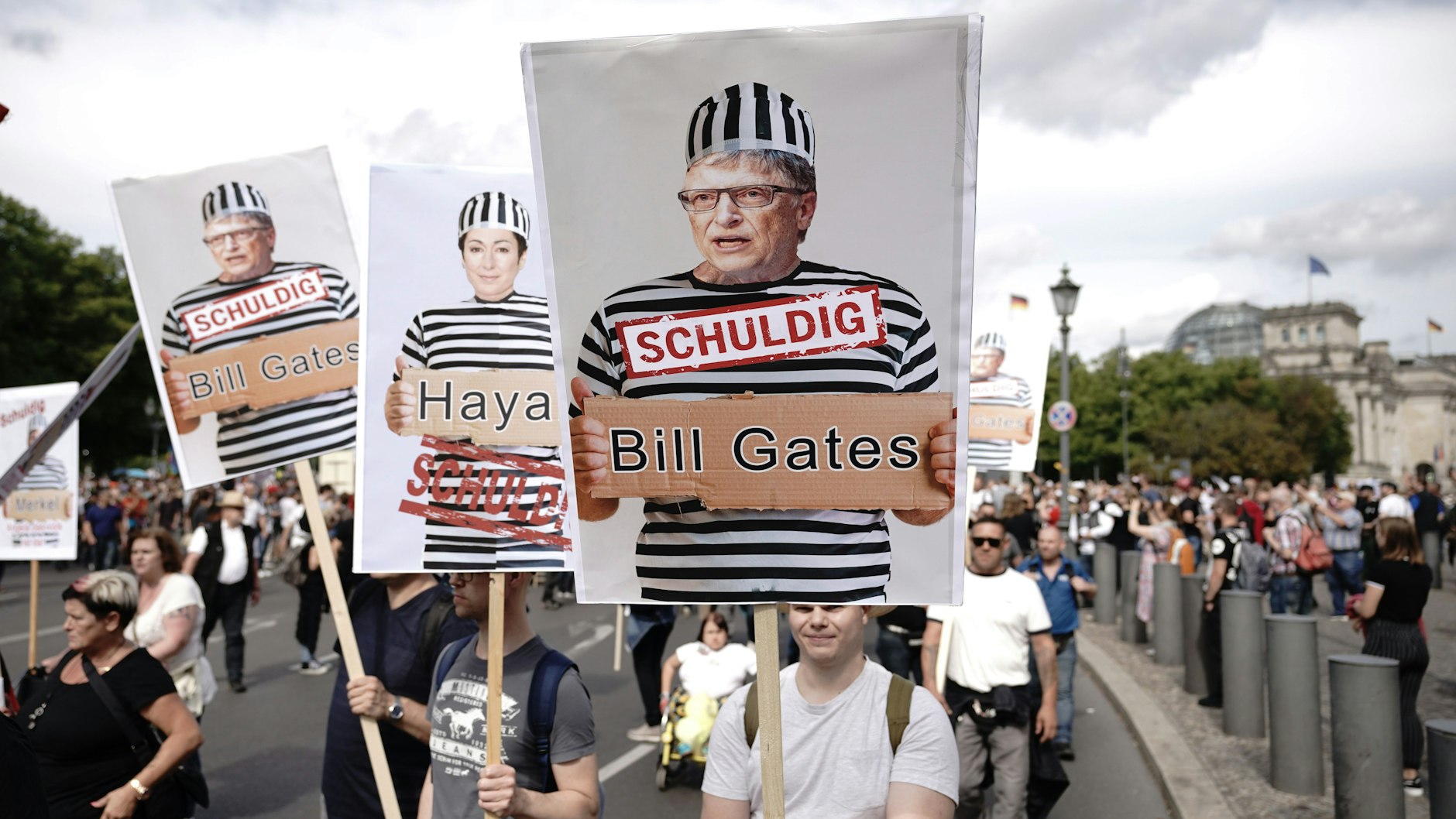 Teilnehmer einer Demonstration gegen die Corona-Maßnahmen in Berlin halten Schilder mit Fotos von Politikern, Journalisten und Wissenschaftlern jeweils mit Namen und „Schuldig“, rechts Microsoft Gründer Bill Gates.