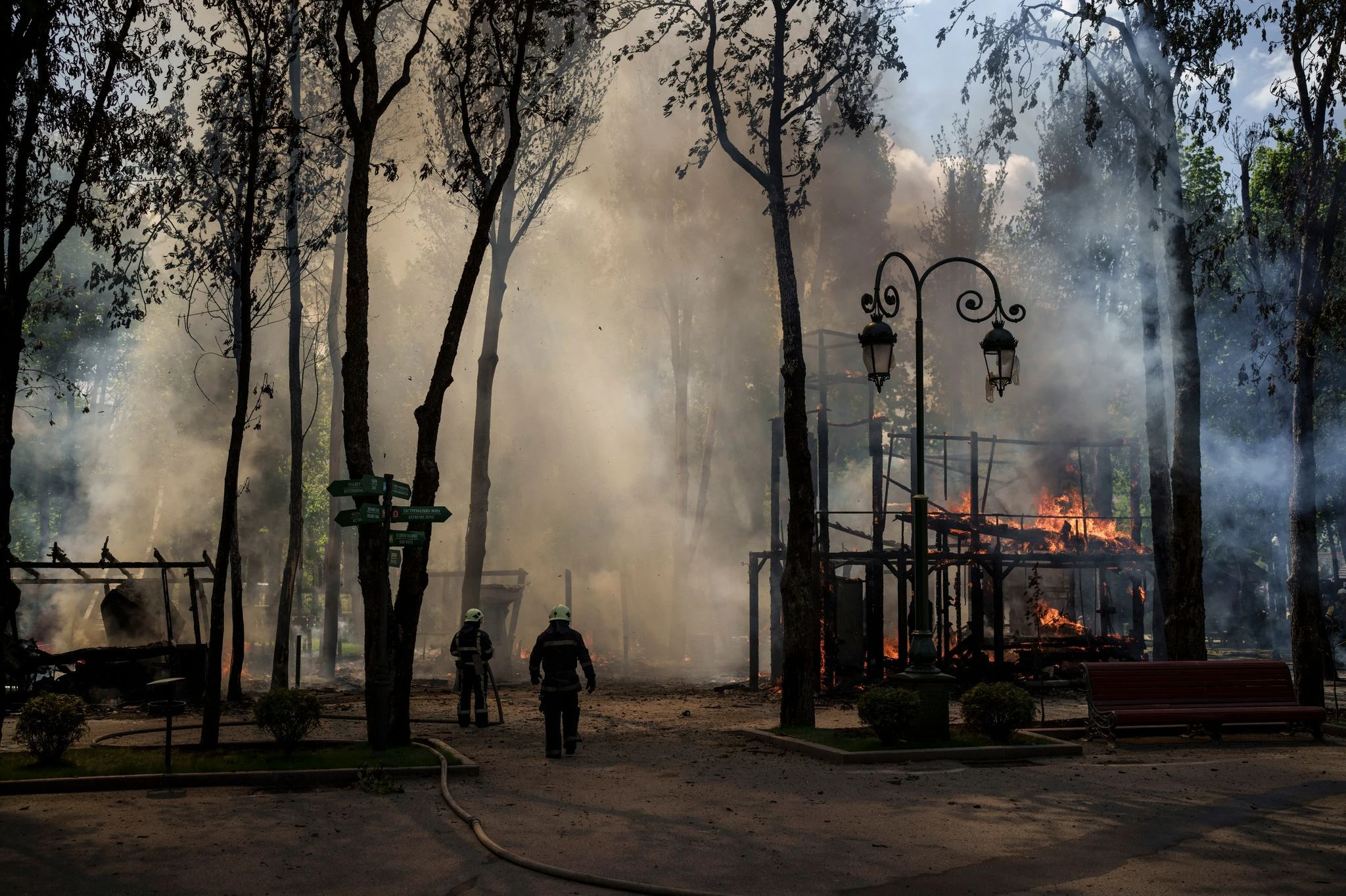 Feuerwehrleute löchen einen Brand, nachdem das russische Militär einen Park in Charkiw bombardiert hat. 