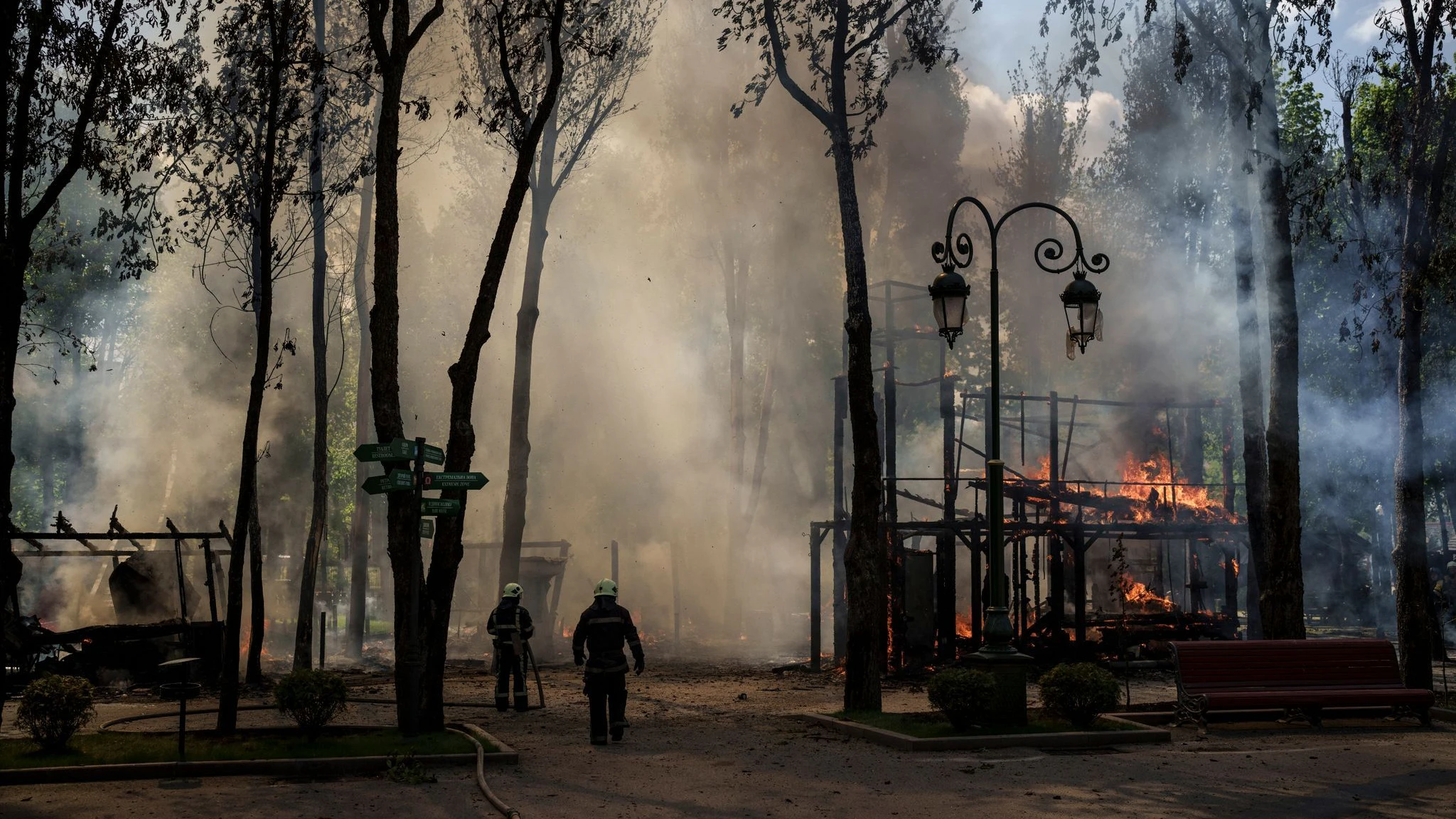 Feuerwehrleute löchen einen Brand, nachdem das russische Militär einen Park in Charkiw bombardiert hat. 