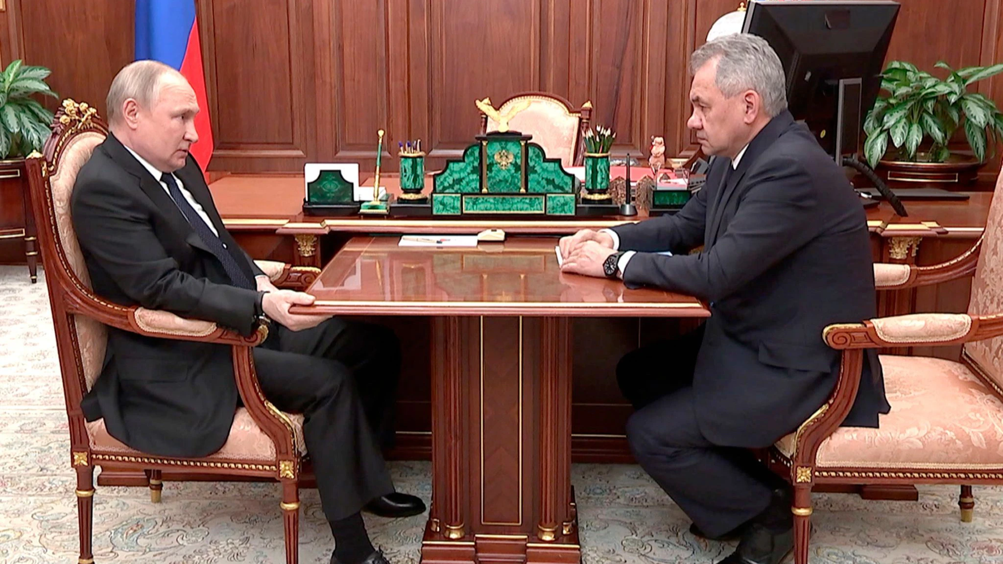 Wladimir Putin mit seinem Verteidigungsminister Sergej Schoigu. Putin klammert sich fast ängstlich an den Tisch.