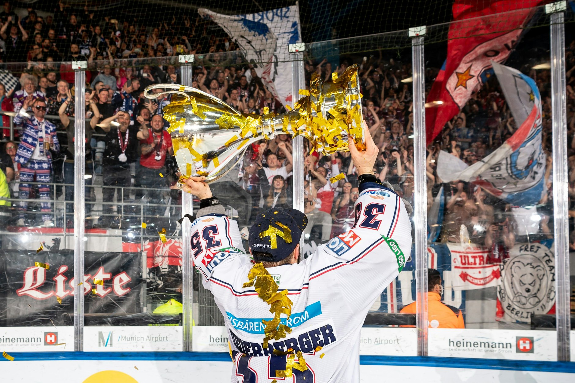 Der überragende Torwart Mathias Niederberger zeigt den mitgereisten Eisbären-Fans in München den Meister-Pokal.