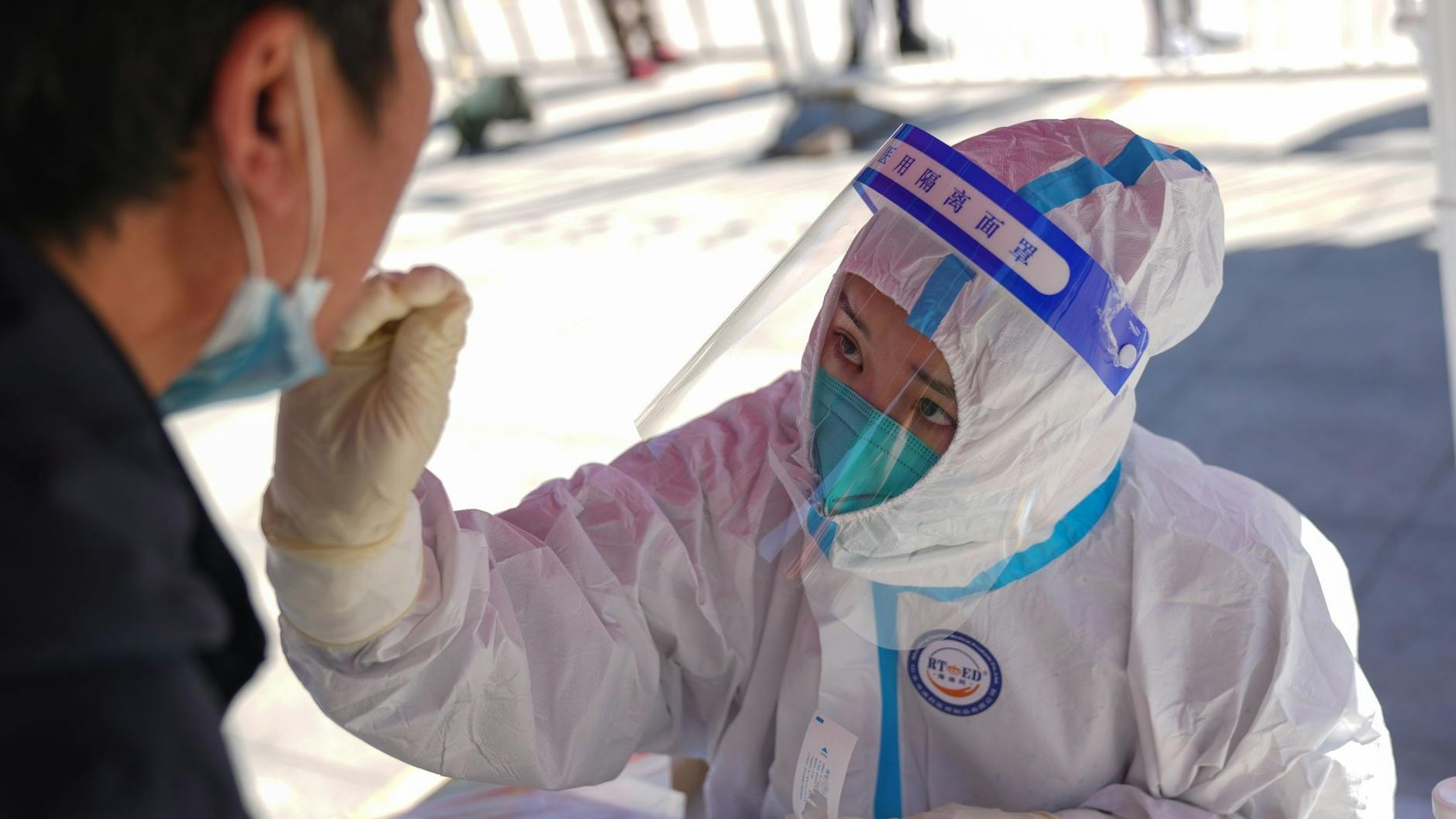 Eine medizinische Angestellte testet einen Anwohner in Pekings Bezirk Daxing auf das Coronavirus.