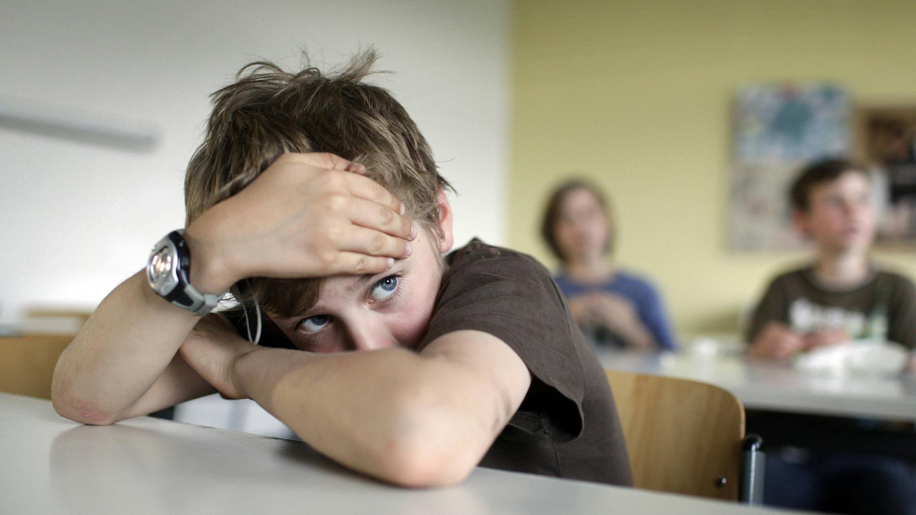 Ein Junge sitzt kränklich im Unterricht (Symbolbild).