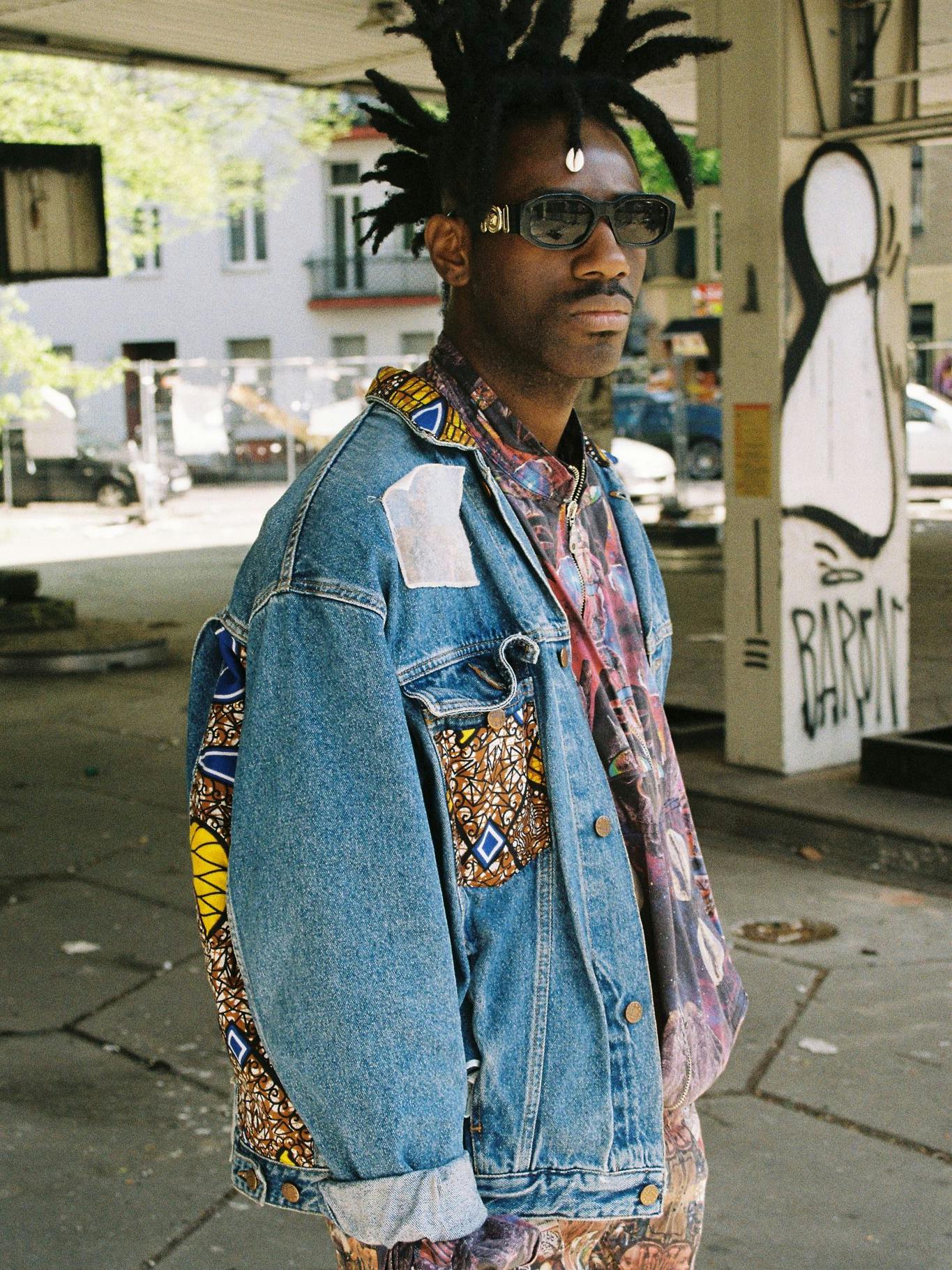 Der Künstler Exocé Kasongo performt zur Musik von Asphalt Djeli’s. Außerdem machg er Mode: Die Entwürfe, die er und die Musiker zum Fotoshoot anhaben, stammen von ihm.