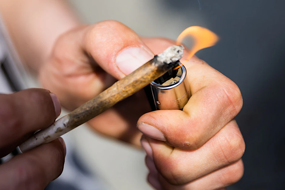 Ein Mann zündet einen Joint an.