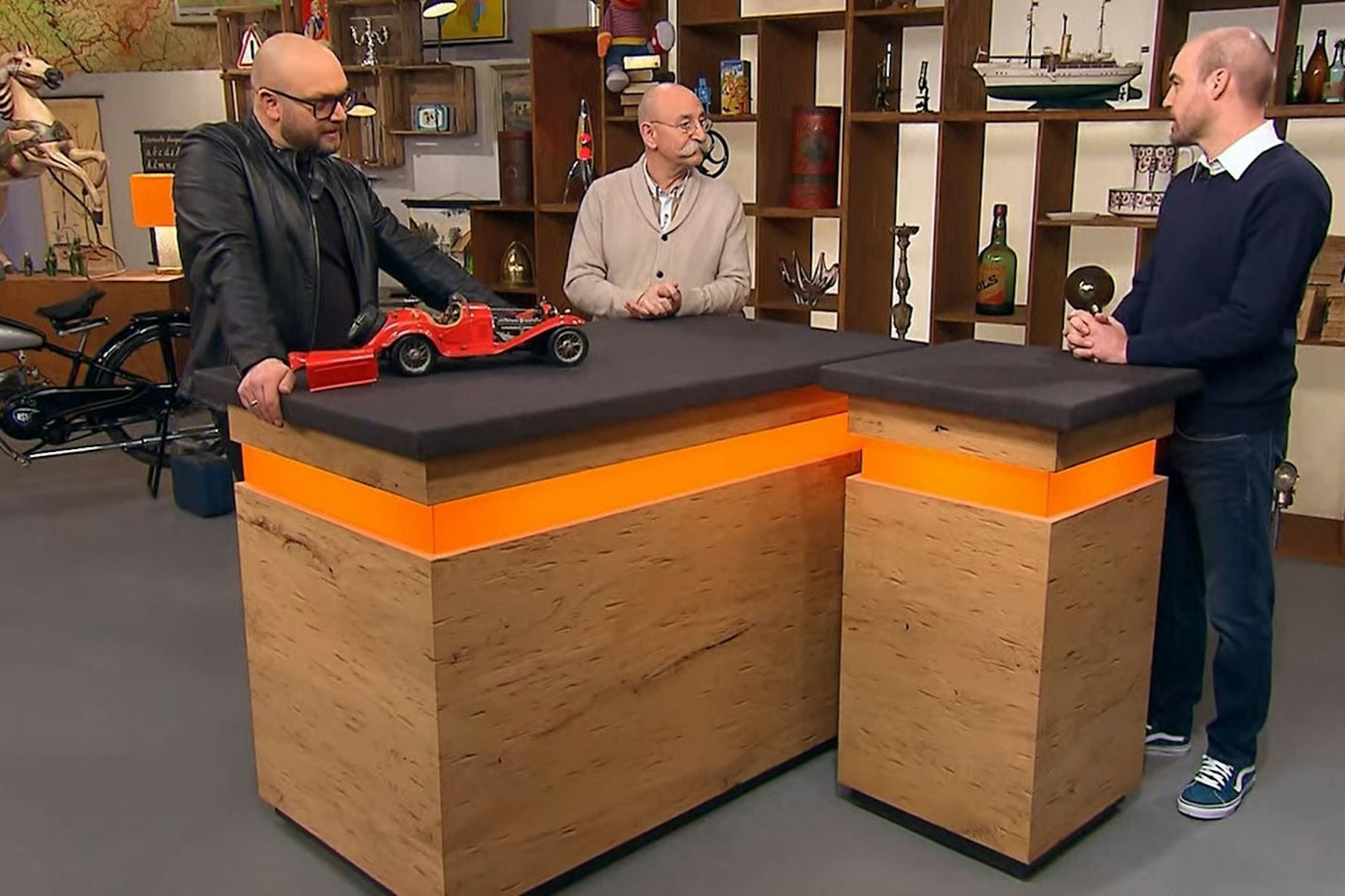 Horst Lichter, Sven Deutschmanek und Tom Eidelmann stehen bei „Bares für Rares“ um ein Modell eines Alfa Romeo 8C herum.