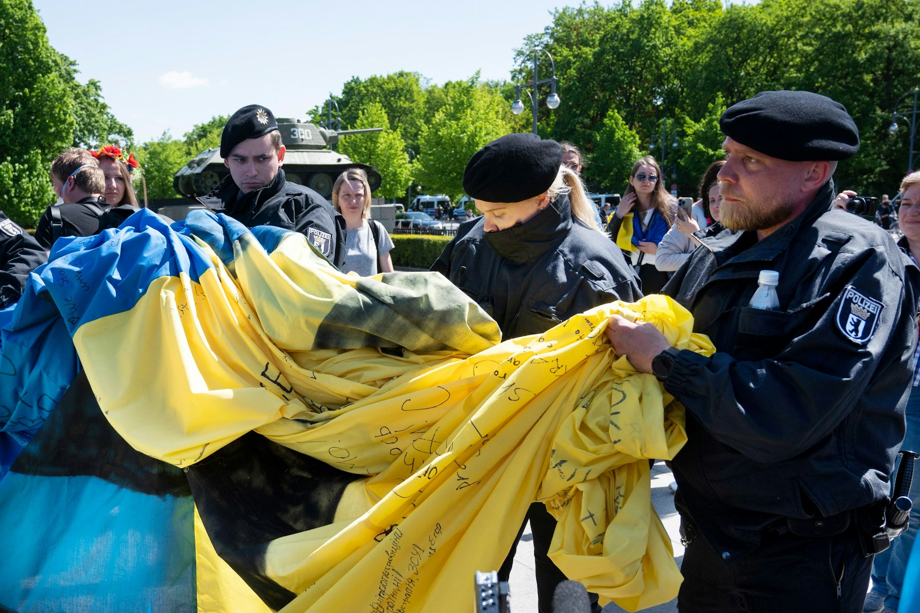 Polizisten wickeln eine große Ukrainische Fahne bei einer Gedenkveranstaltung vor dem Sowjetischen Ehrenmal im Tiergarten zusammen.