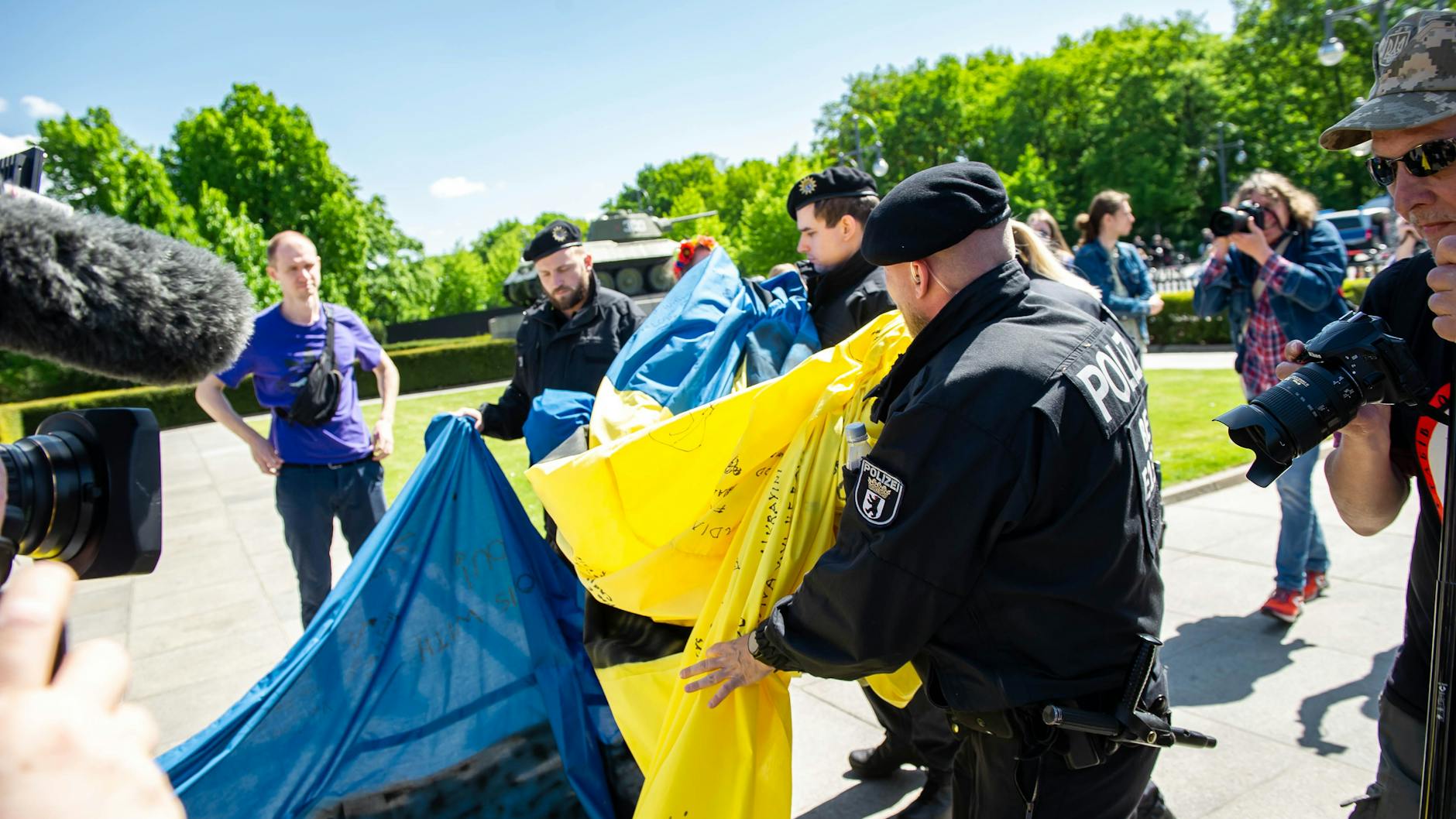 Polizisten rollen die 25 Meter lange Ukraine-Flagge ein.