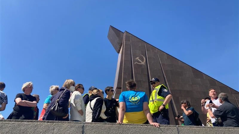 Auch am Ehrenmal Treptower Park wird ein Mann in den Farben der Ukraine von der Polizei angesprochen.