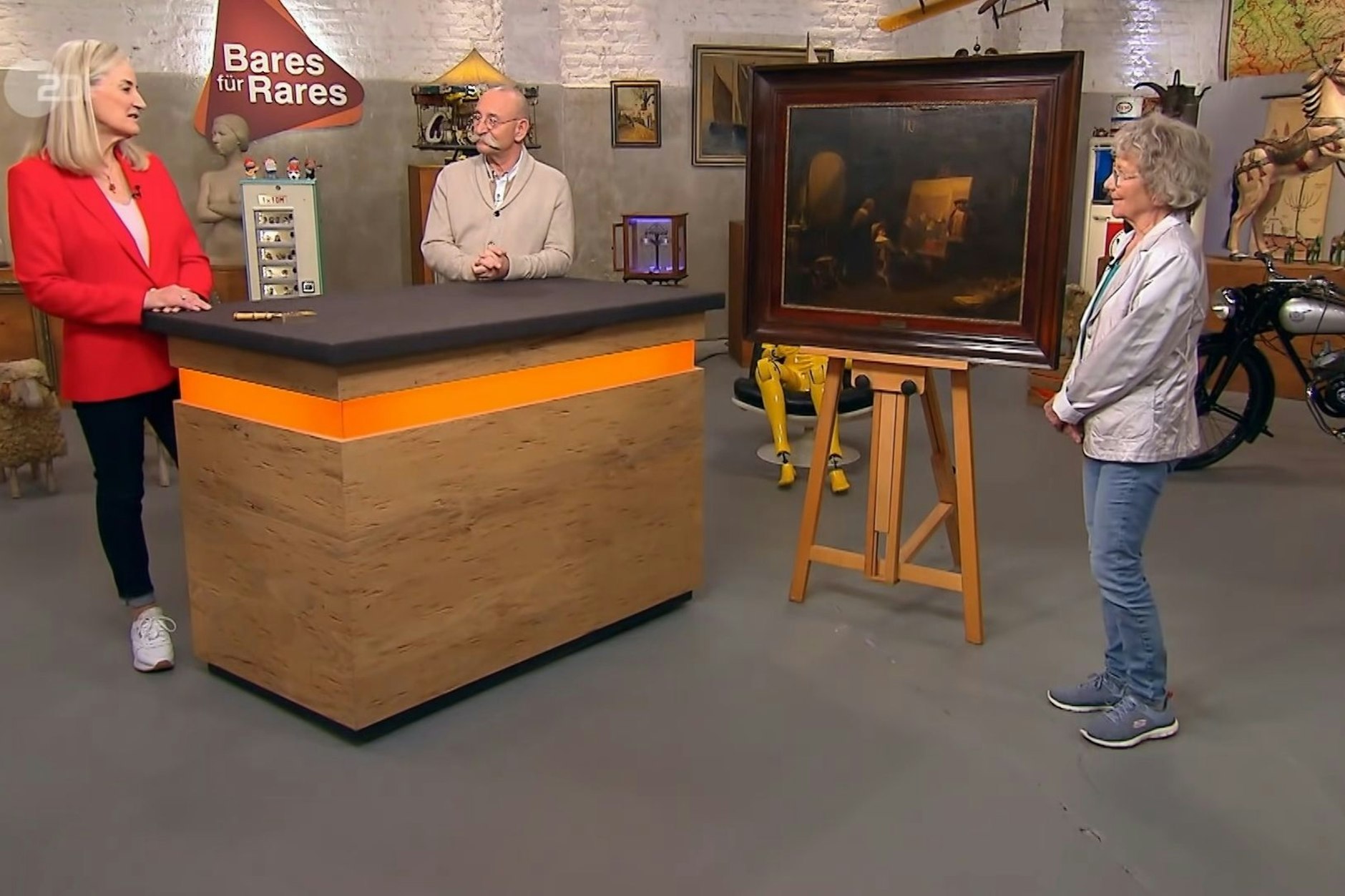 „Bares für Rares“-Expertin Dr. Friederike Werner nimmt das dunkel gehaltene Öl auf Holz genauestens unter die Lupe.
