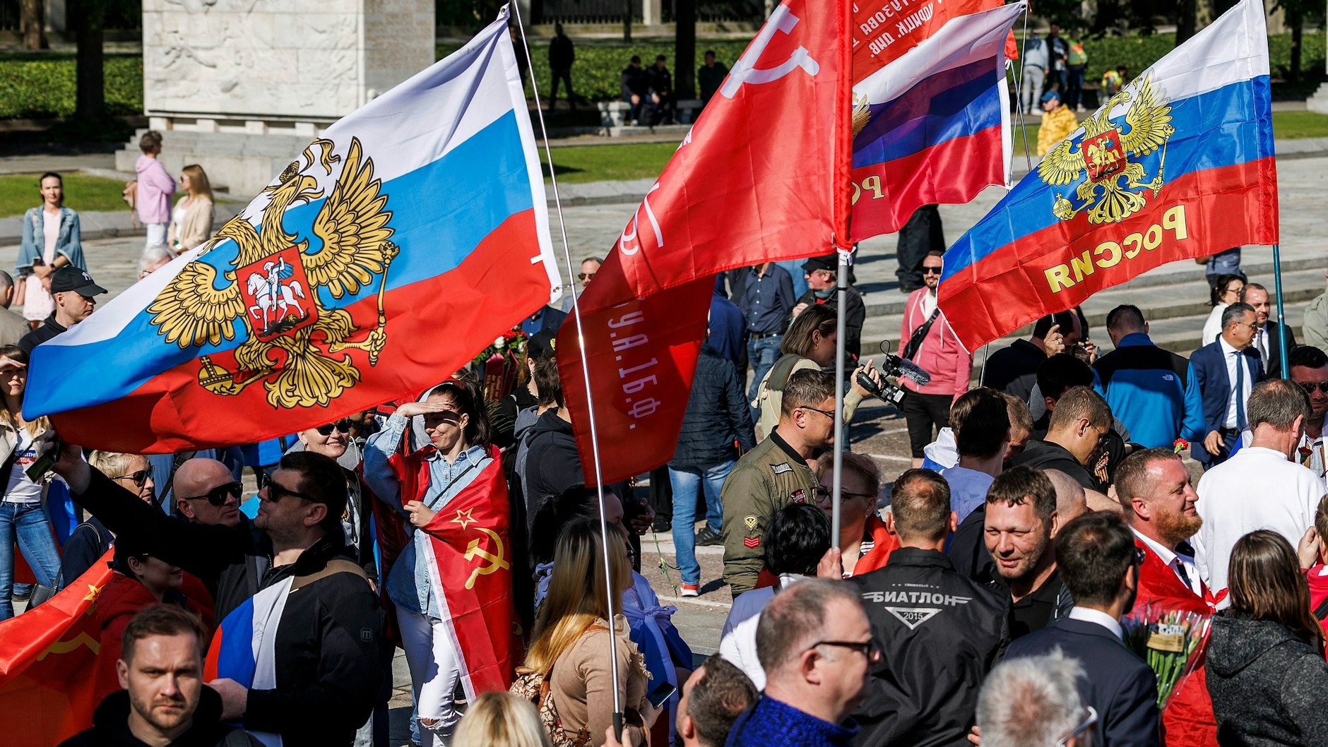 Menschen schwenken bei einer Gedenkveranstaltung am sowjetischen Ehrenmal im Treptower Park russische und sowjetische Fahnen.