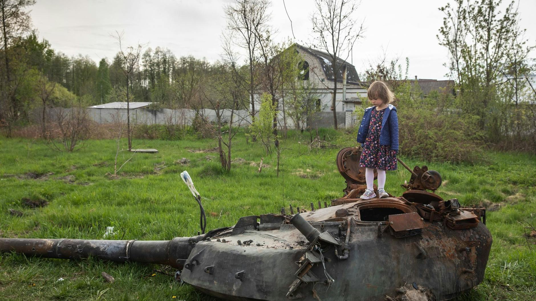 Ein Mädchen steht auf dem Turm eines zerstörten russischen Panzers in einem Dorf nahe Kiew.