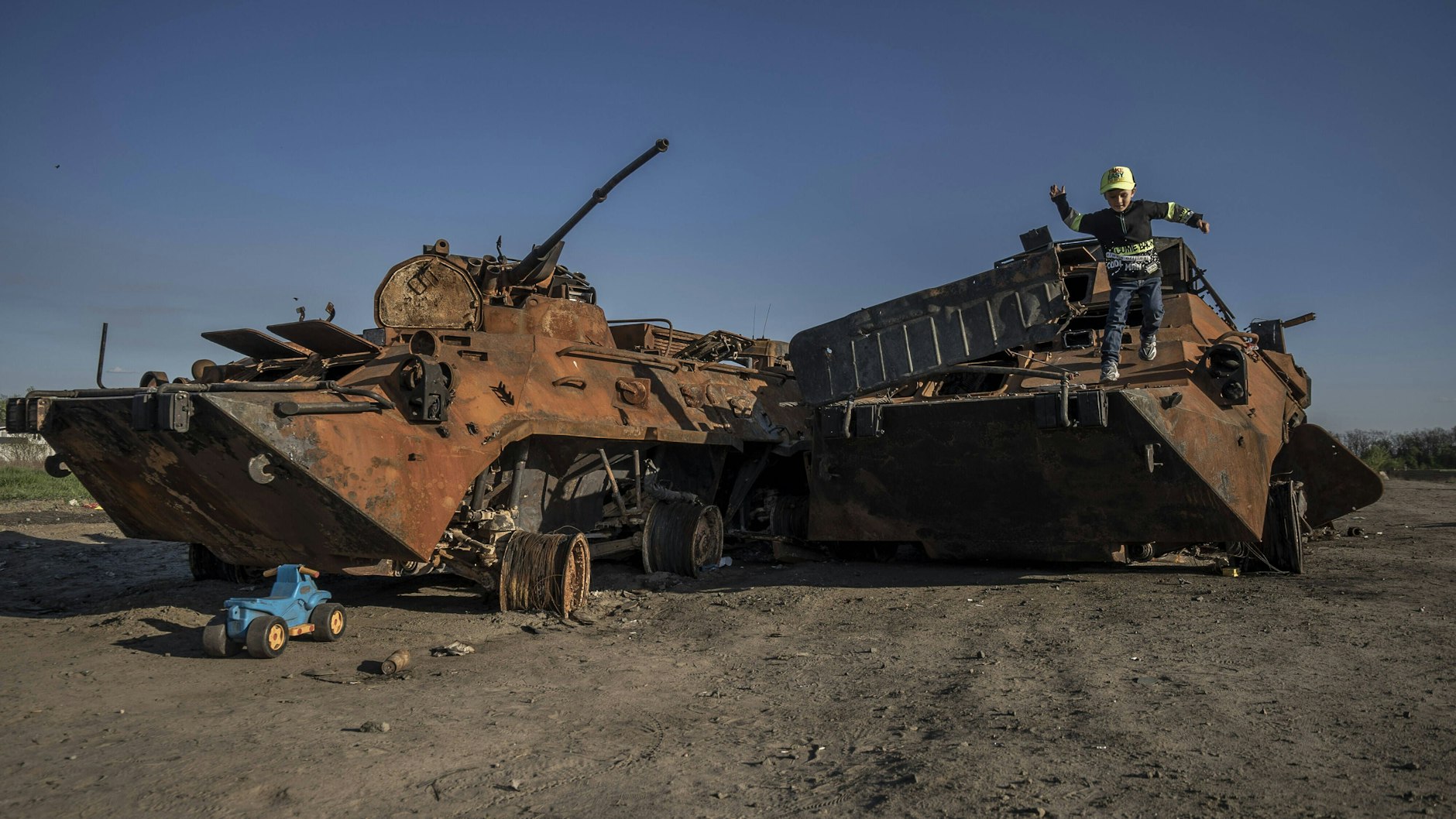 Ein kleiner Junge spielt auf einem ausgebrannten russischen Panzer, der auf einem provisorischen Parkplatz in der Nähe von Irpin, Ukraine, abgestellt wurde.