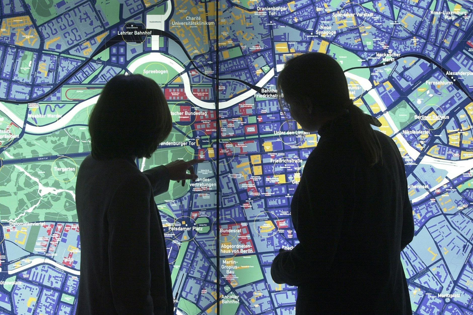 Frauen vor einem erleuchteten Stadtplan Berlins: Viele Berliner Bauprojekte ließen sich günstiger realisieren.
