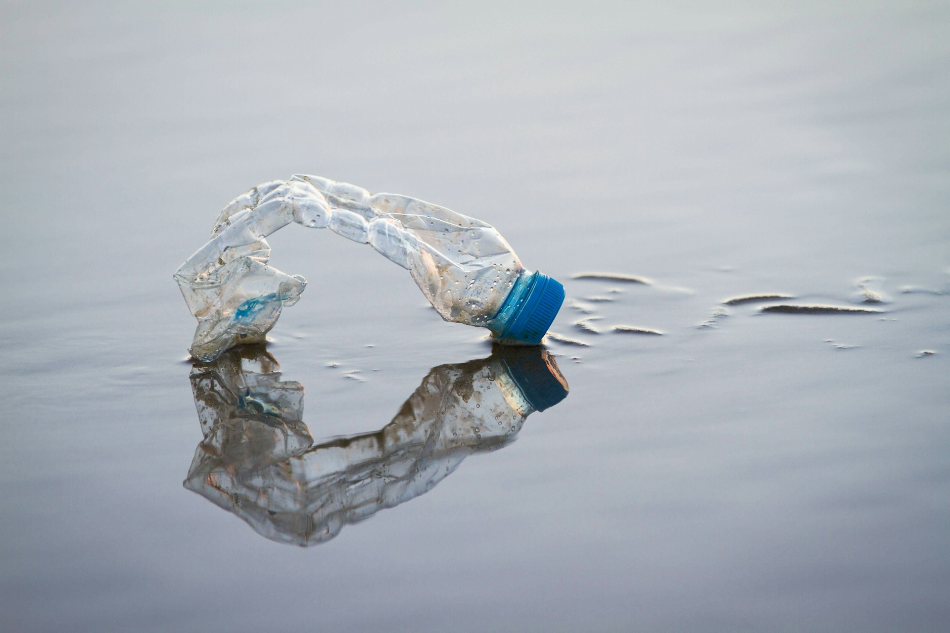Eine leere Plastikflasche liegt am Strand.