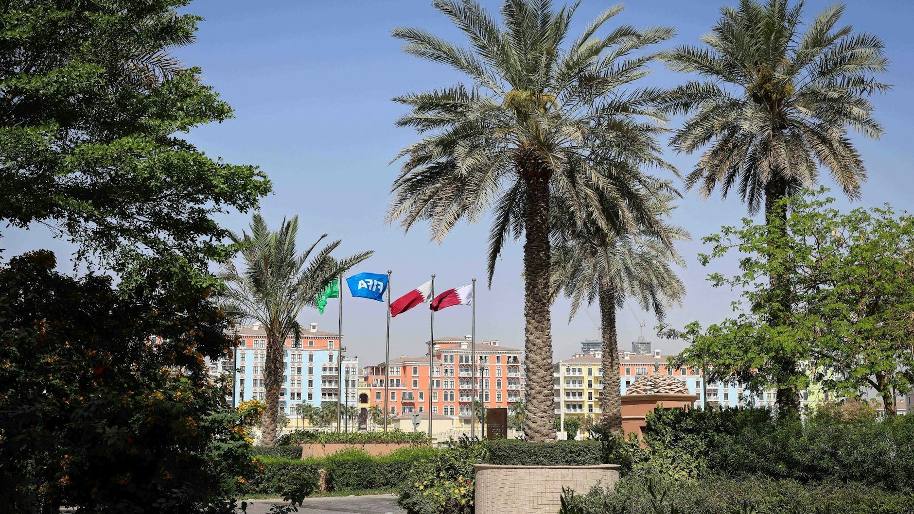 Die Flaggen Katars und der Fifa wehen vor einer Hotelanlage in Doha.
