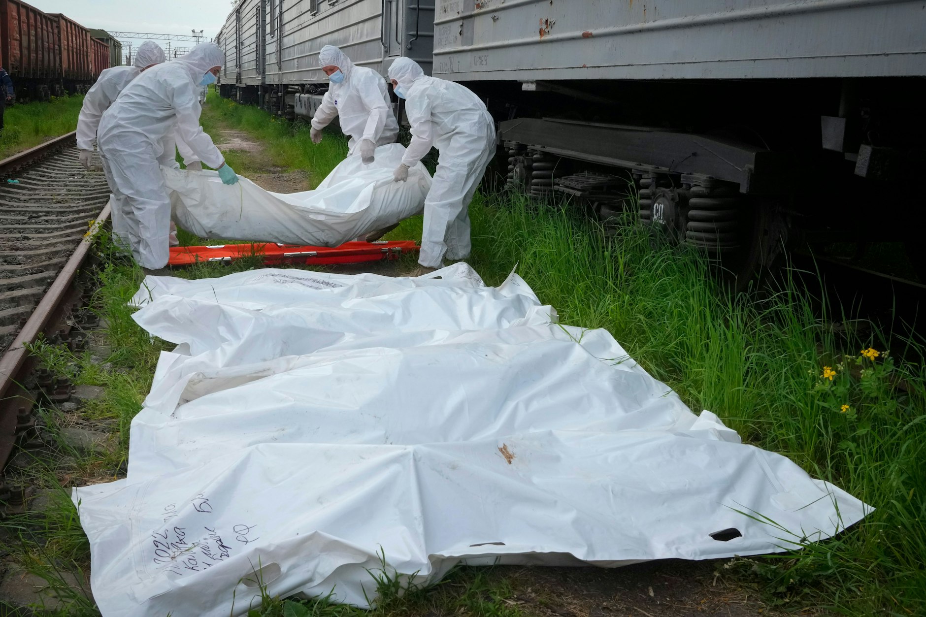 Ukrainische Soldaten in Schutzanzügen verladen die Leichen der Soldaten in die Kühlwaggons.