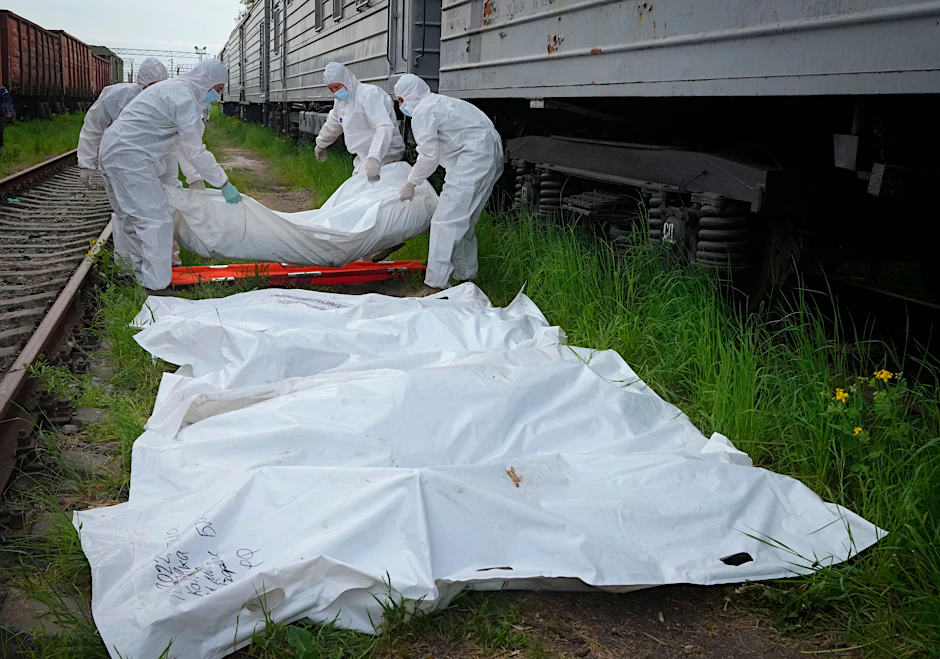 Ukrainische Soldaten in Schutzanzügen verladen die Leichen der Soldaten in die Kühlwaggons.