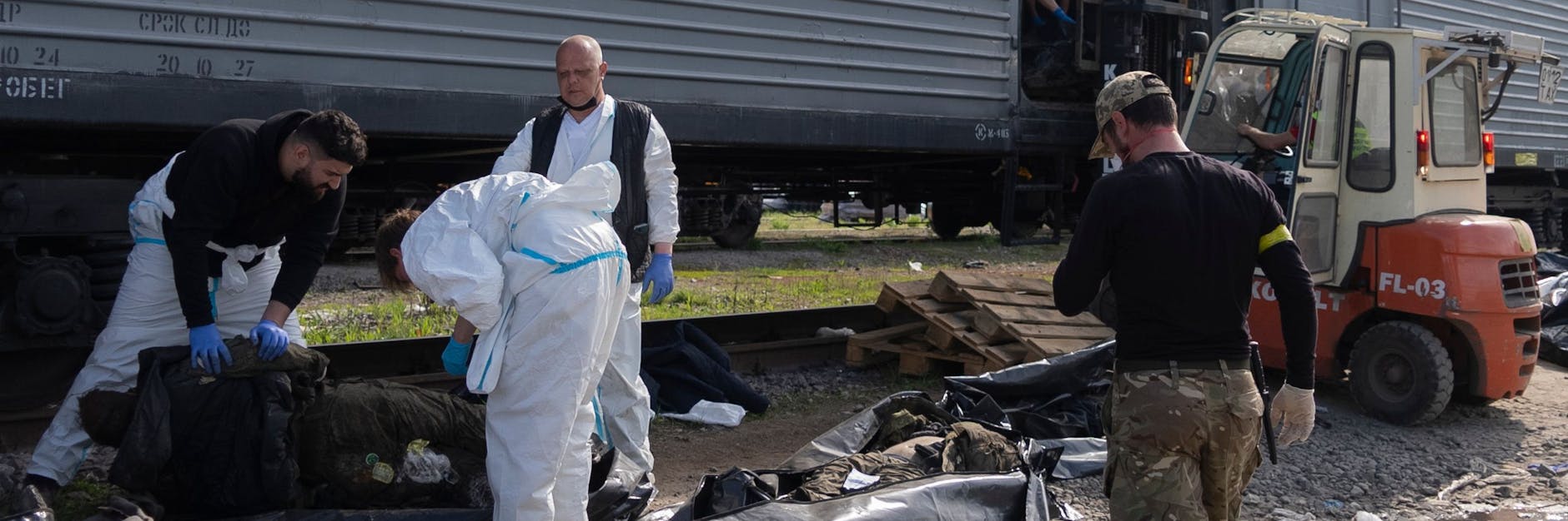 Ukrainische Gerichtsmediziner vor einem Kühl-Waggon: Davor tote russische Soldaten, die identifziert werden sollen.