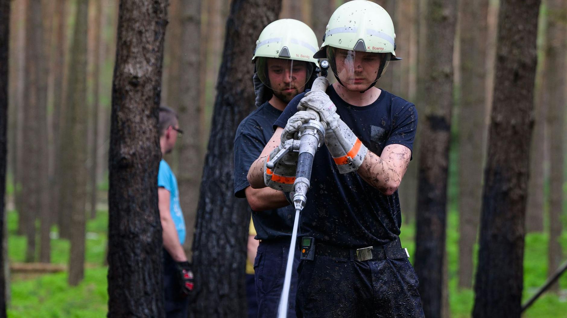 Einsatzkräfte der Feuerwehr löschen Glutnester nach einem Waldbrand.