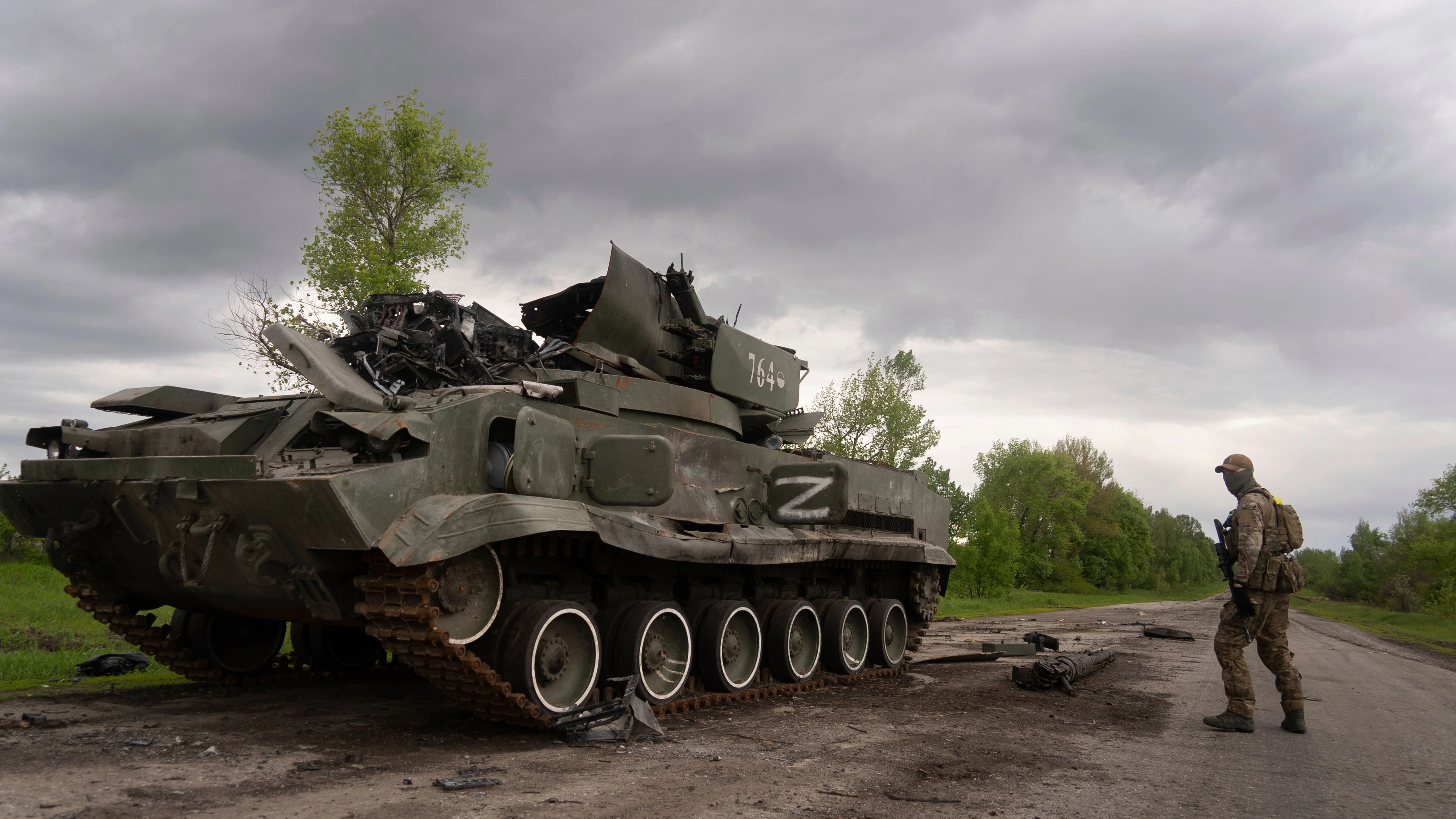 Ein ukrainischer Soldat geht an einem zerstörten russischen APC Panzer in der Nähe von Kutusiwka, nördlich von Charkiw, im Osten der Ukraine, vorbei.
