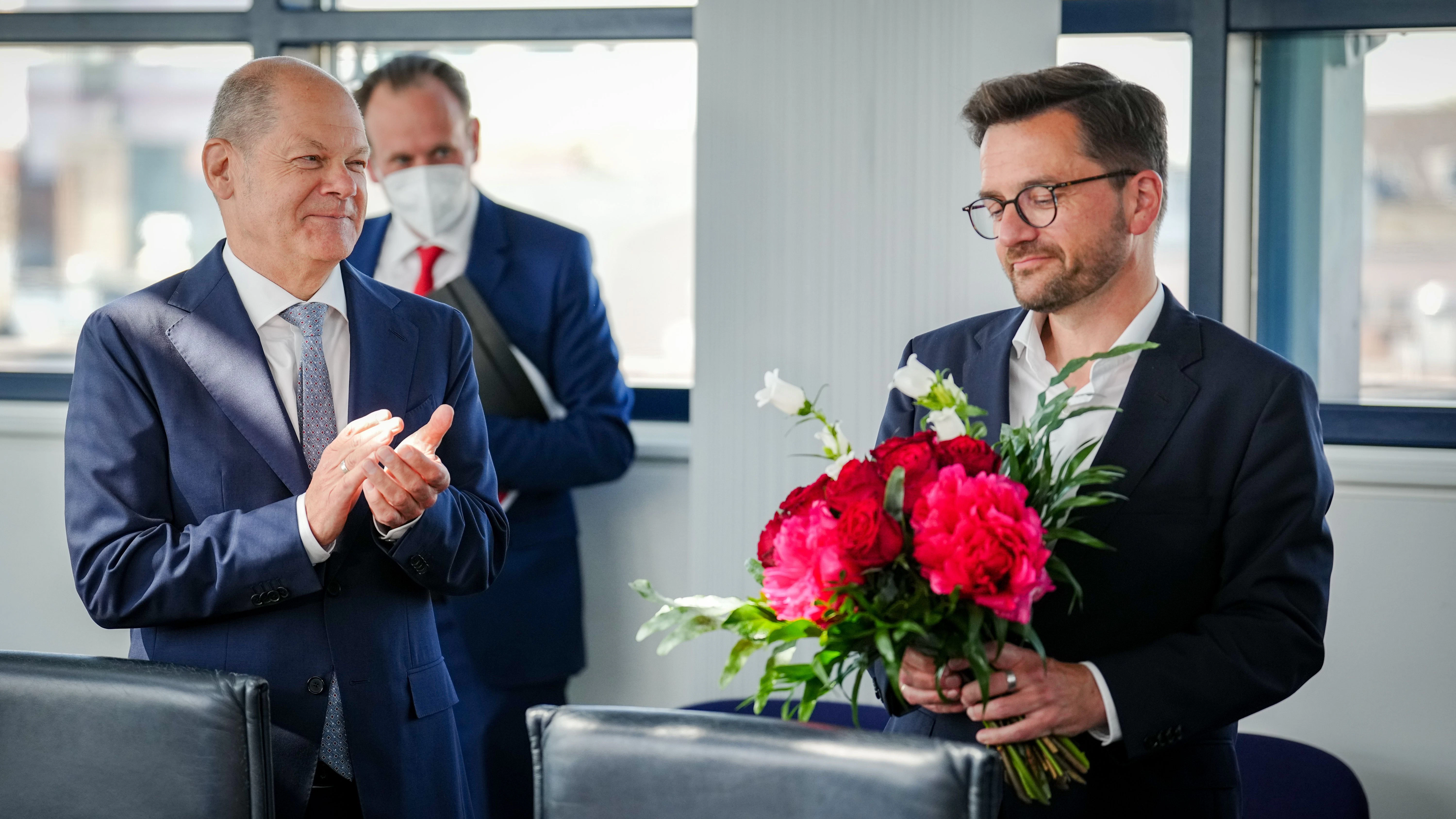 Versonnen blickt Thomas Kutschaty auf einen Blumenstrauß, während Kanzler Scholz dem Wahlverlierer bei der SPD-Präsidiumssitzung am Montag in Berlin&nbsp; applaudiert.