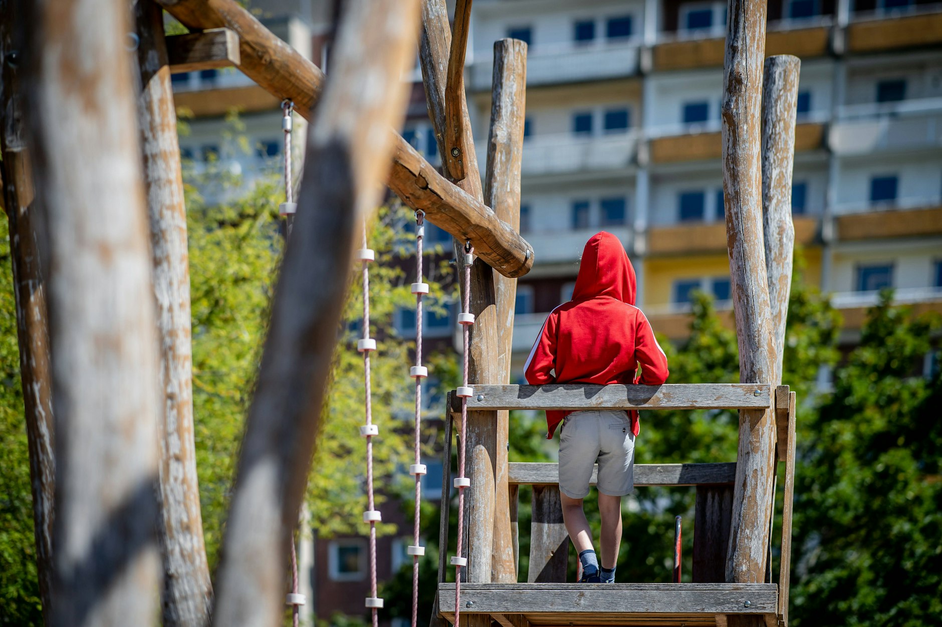 Ein Kind steht auf einem Spielplatz vor einem Plattenbau in Leipzig. Kinder in armen Familien fahren nicht in den Urlaub.