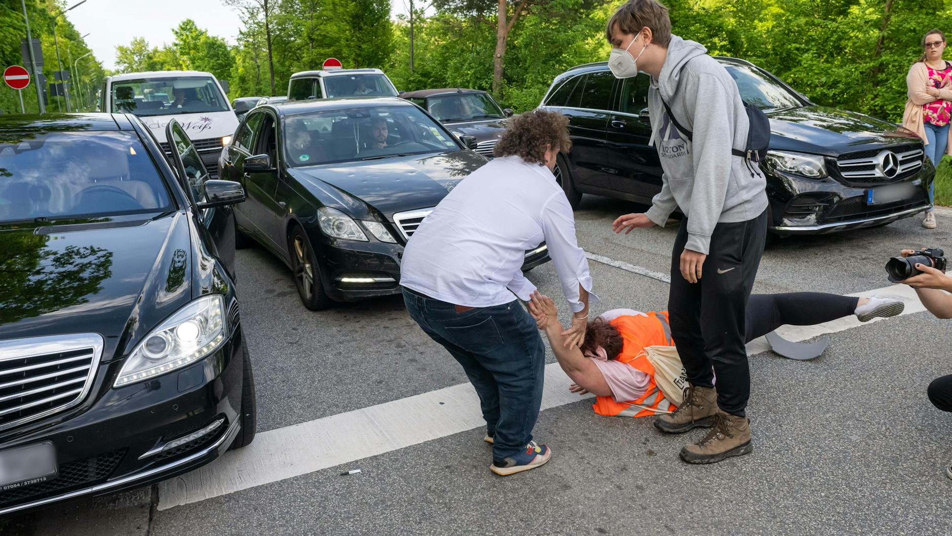 Ein aufgebrachter Autofahrer zieht einen Demonstranten von der Fahrbahn.