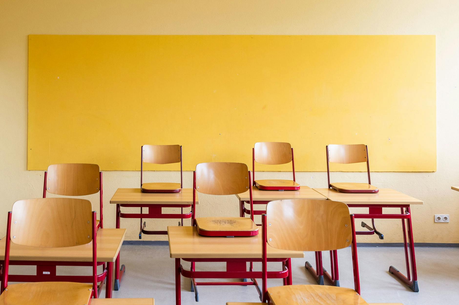 Hochgestellte Stühle stehen auf den Tischen in einem leeren Klassenzimmer.