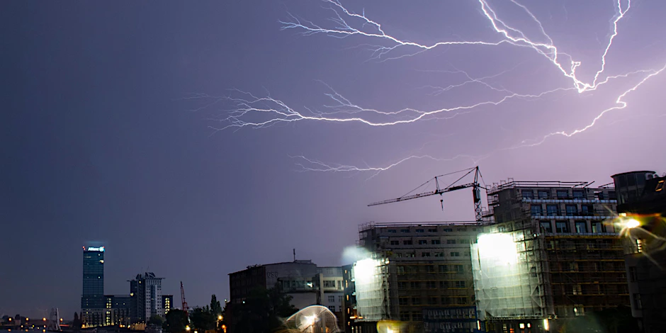 Blitze zucken während eines Gewitters unweit des Allianz-Hochhauses über den Himmel.