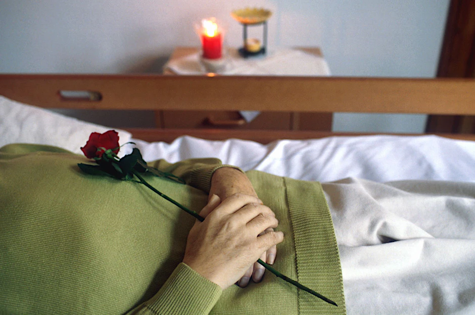 Eine Verstorbene Frau mit einer Rose in der Hand.
