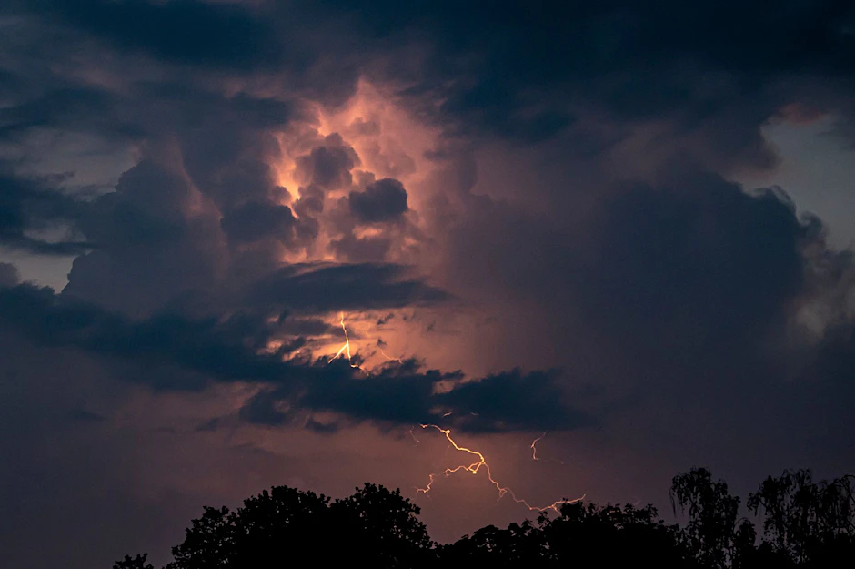 Ein Blitz hellt hinter dunklen Wolken auf.