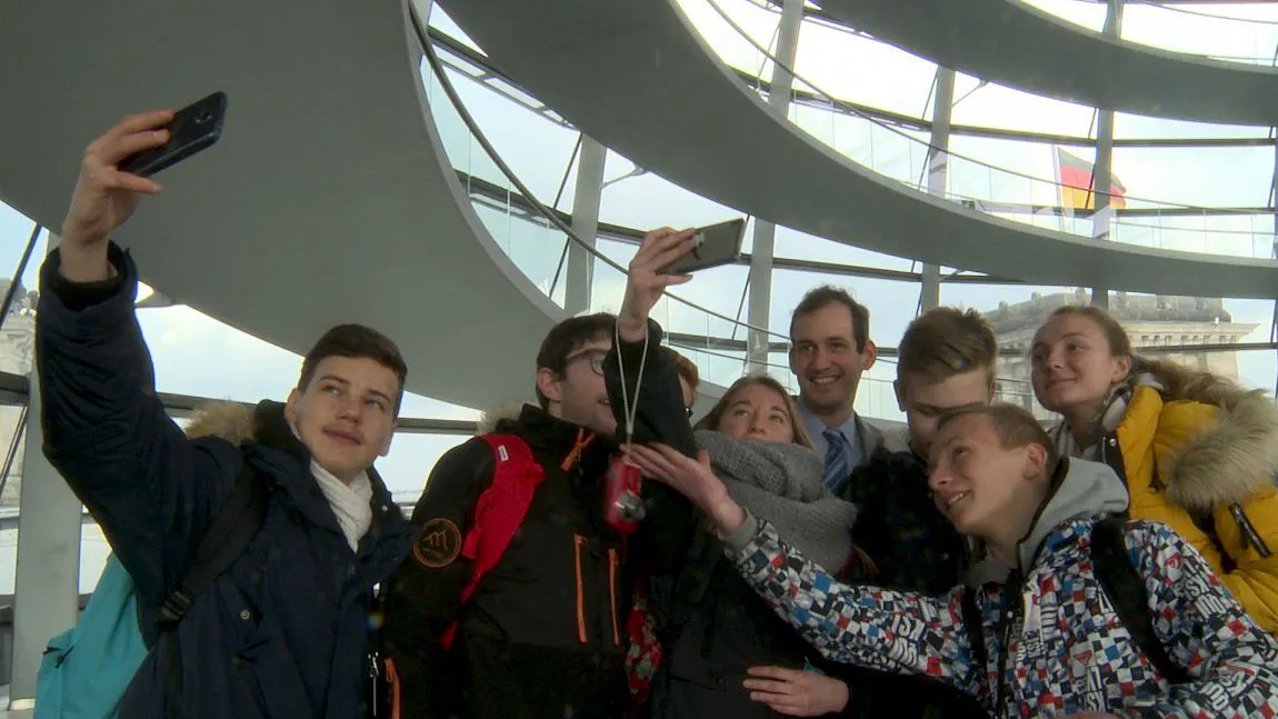 Norbert Kleinwächter, Lehrer und AfD-Politiker, lächelt im Bundestag in die Selfie-Kameras. Die Szene stammt aus Andreas Wilckes Dokumentarfilm „Volksvertreter“.