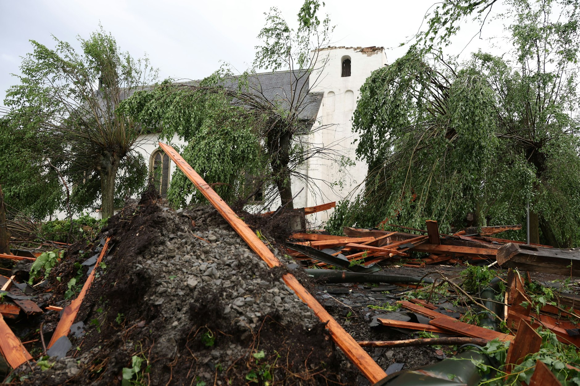 Trümmer liegen vor der katholischen Kirche St. Clemens in Hellinghausen bei Lippstadt, deren Spitze zerstört wurde. Ein mutmaßlicher Tornado hat in Lippstadt am Freitagnachmittag massive Schäden verursacht.