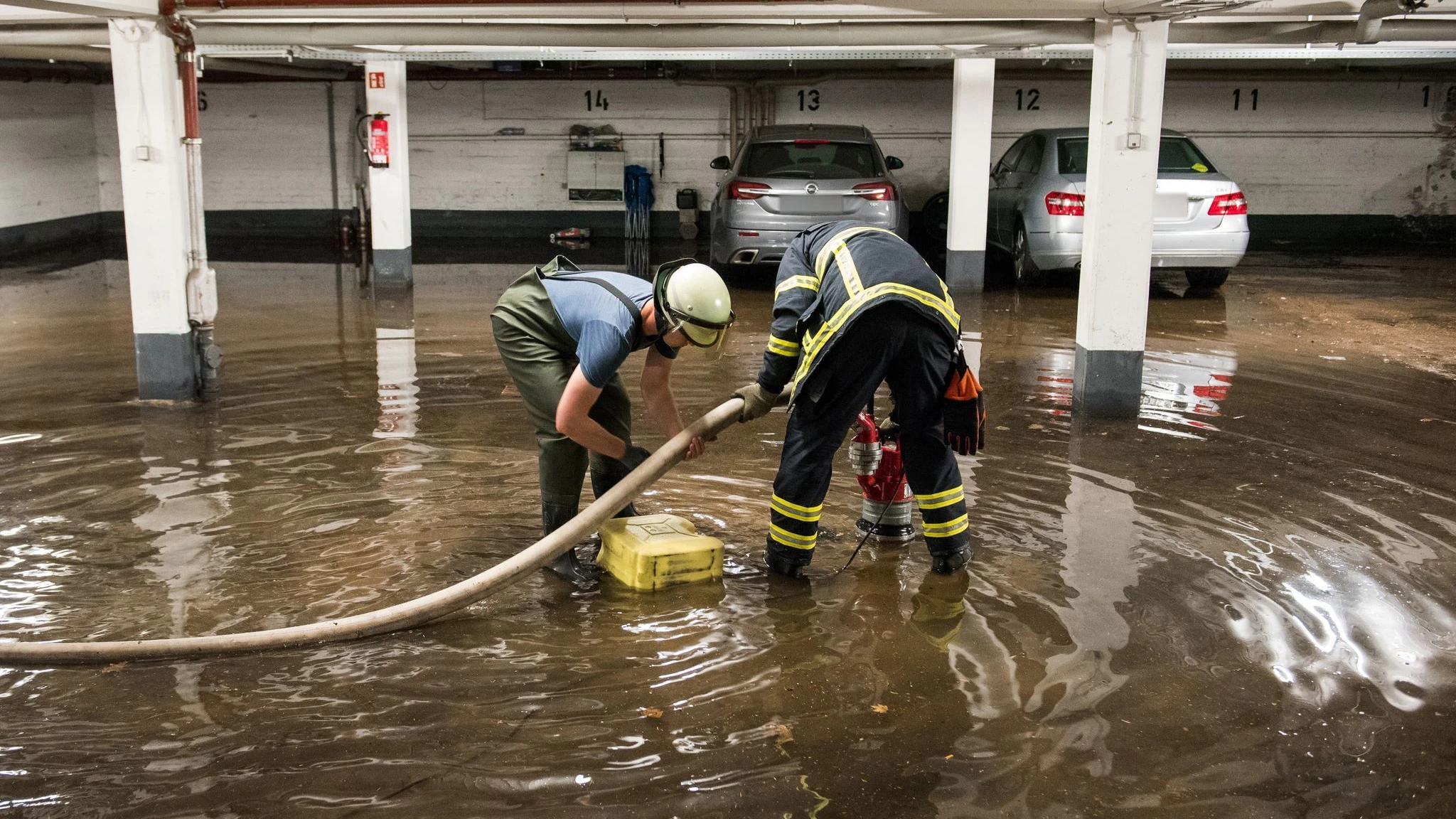 Feuerwehrleute pumpen in Hamburg Wasser aus einer überfluteten Tiefgarage ab.