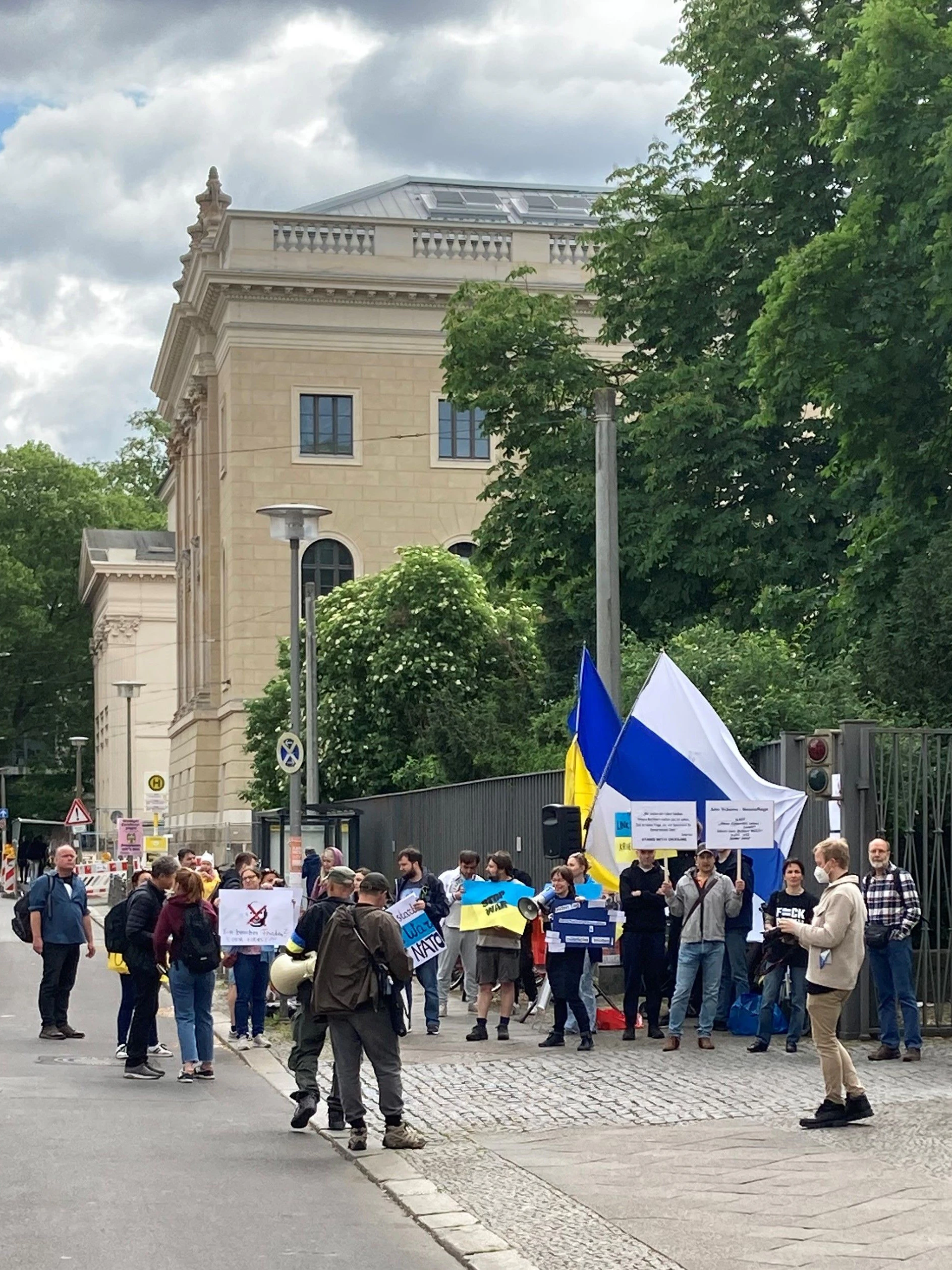Pro-ukrainische Demonstranten vor dem Hintereingang der Humboldt-Universität. Im Hintergrund wehen eine ukrainische Flagge sowie eine Fahne der russischen Anti-Kriegsbewegung.