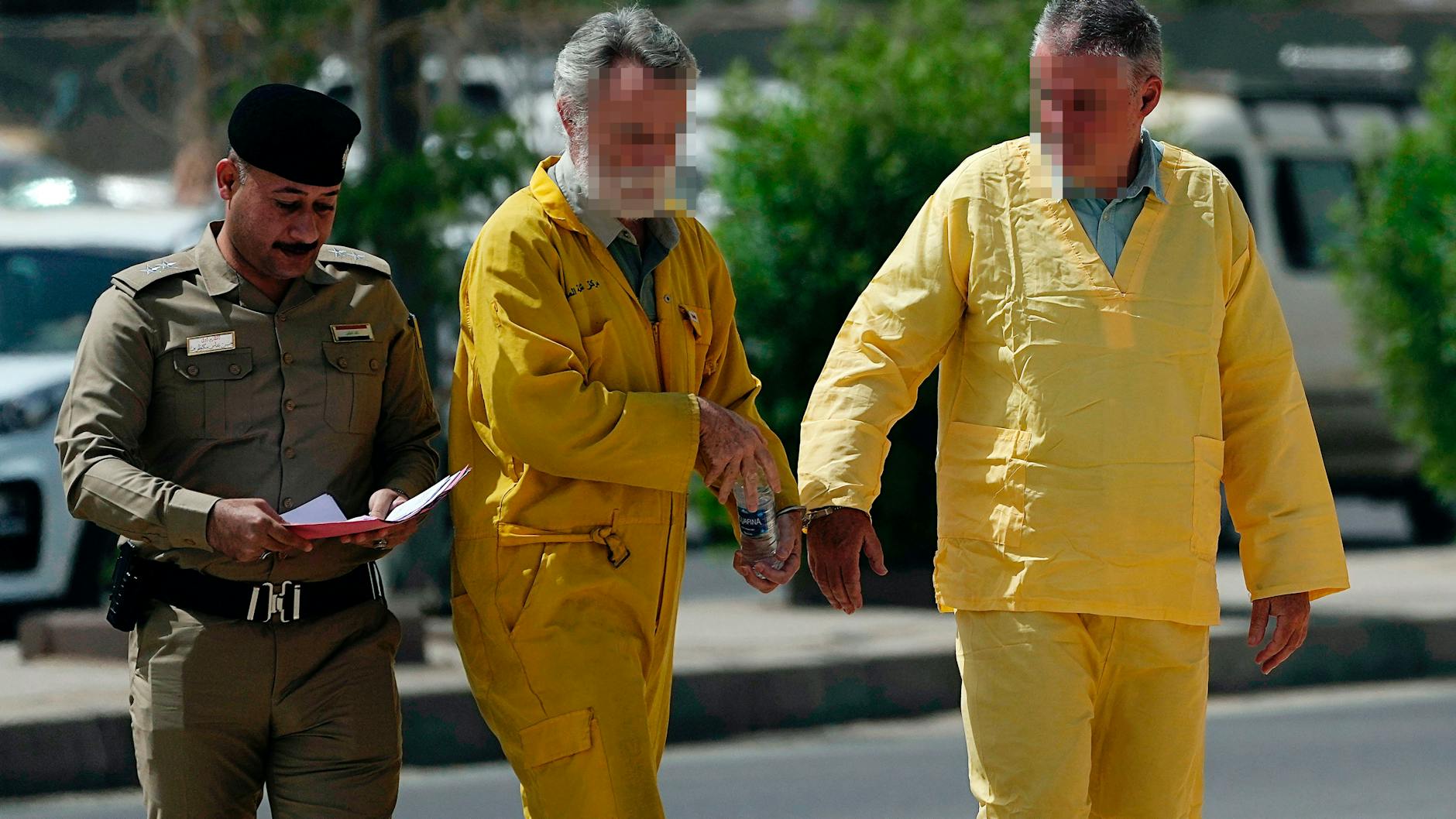Der Berliner Volker W. (r.) und der Brite Jim F. werden in Bagdad in Handschellen in einen Gerichtssaal geführt. Beide gaben an, ihnen sei das Gesetz über den Schmuggel von Antiquitäten nicht bekannt gewesen.