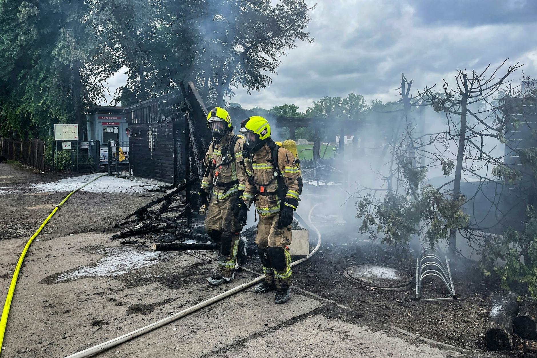 Einsatzkräfte der Feuerwehr verlassen unter Atemschutz das Gelände des Sportvereins in Berlin-Köpenick.